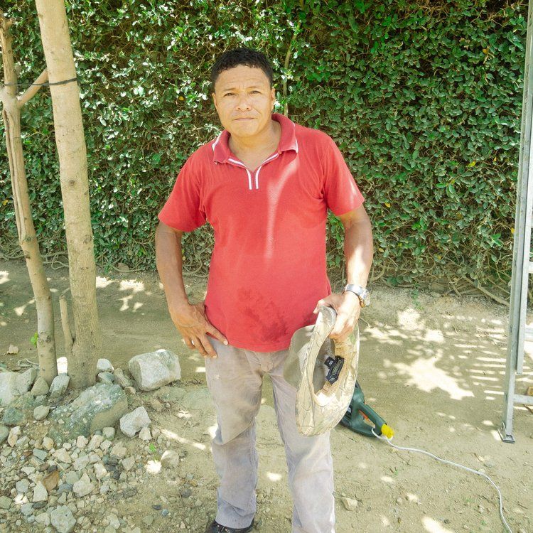 A man in a red shirt is holding a hat