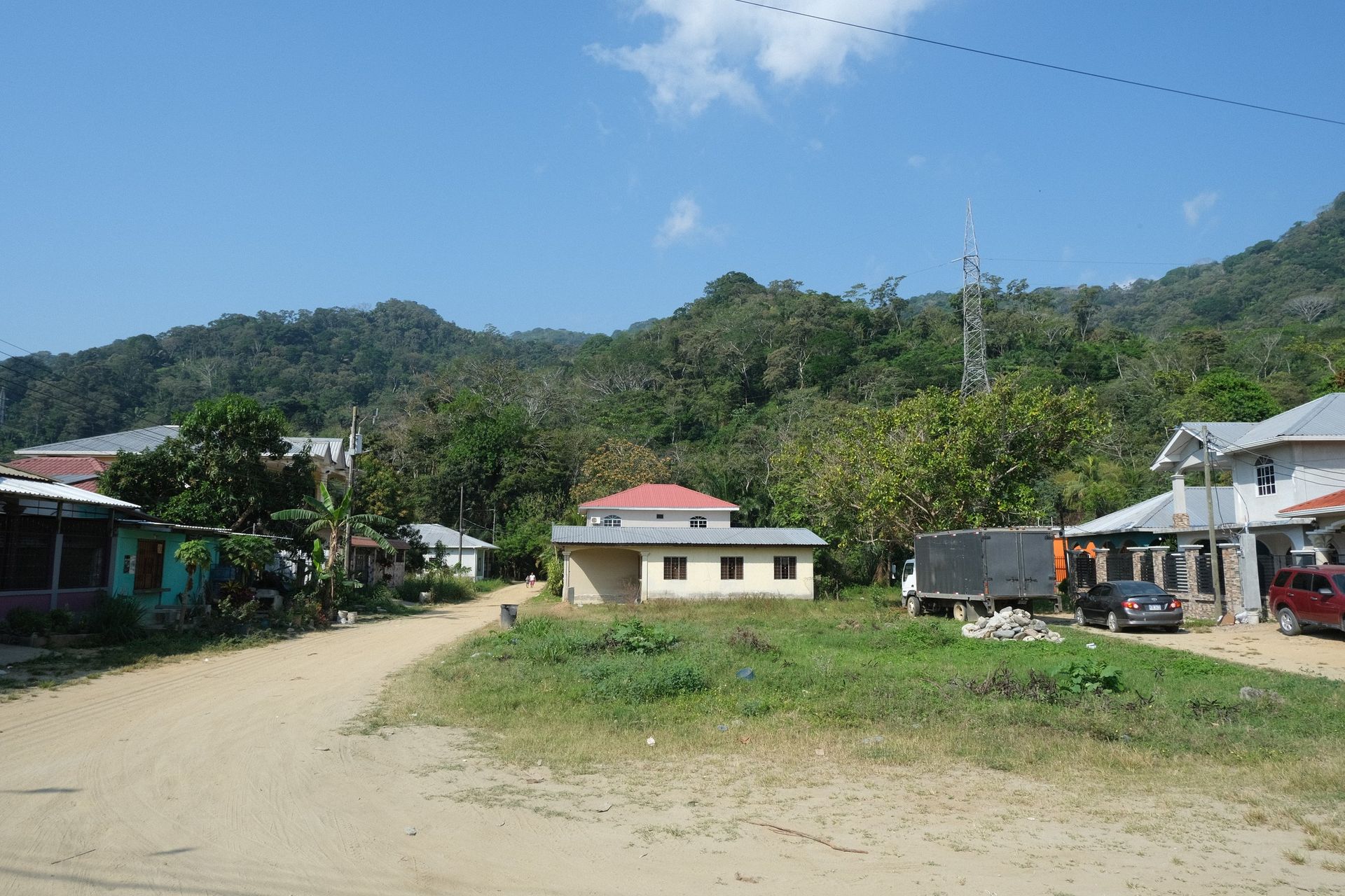 A dirt road going through a small village with mountains in the background