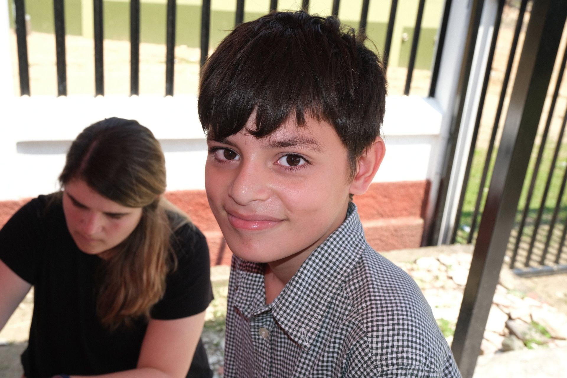 A young boy is smiling for the camera while a woman looks on.