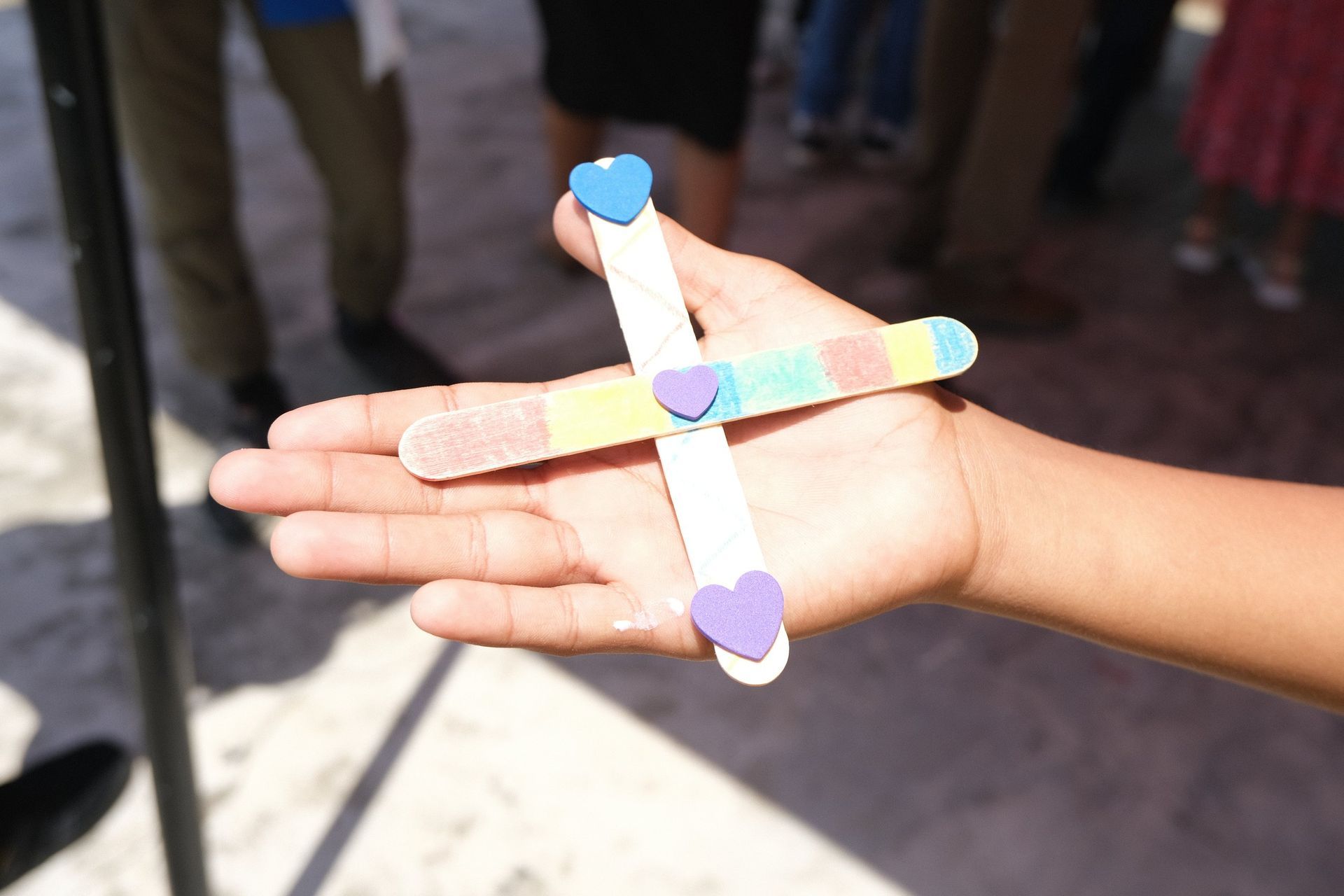A person is holding a cross made out of popsicle sticks