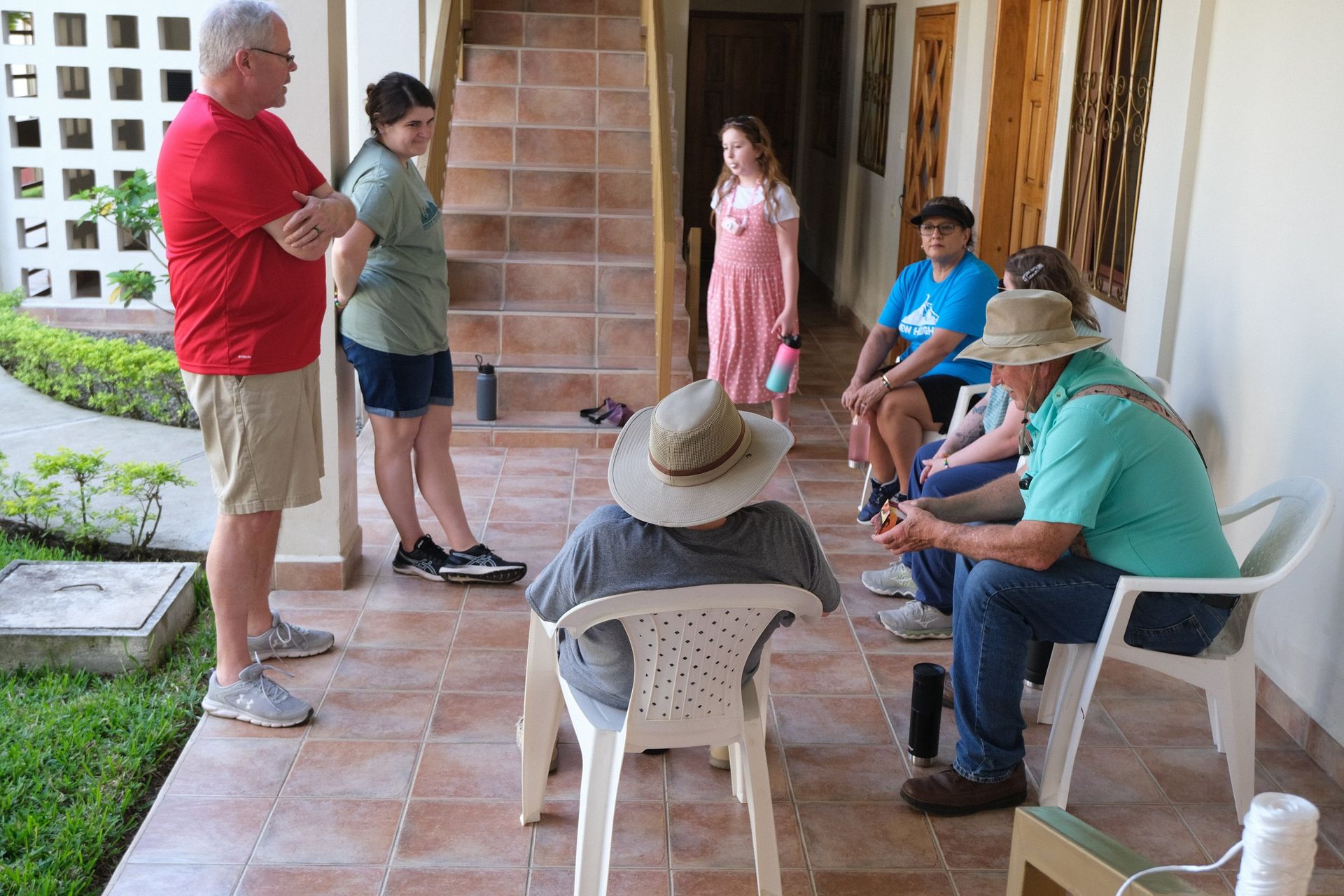 A group of people are sitting on a porch talking to each other