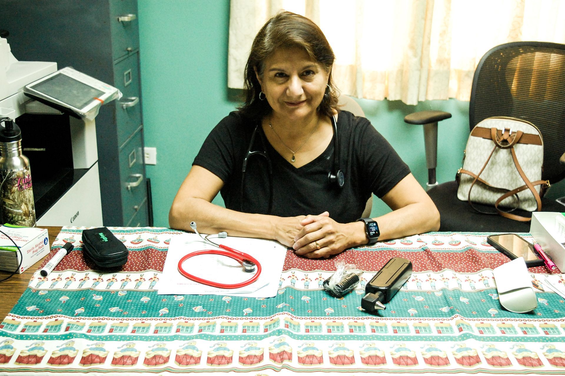 A woman is sitting at a desk with a stethoscope on it