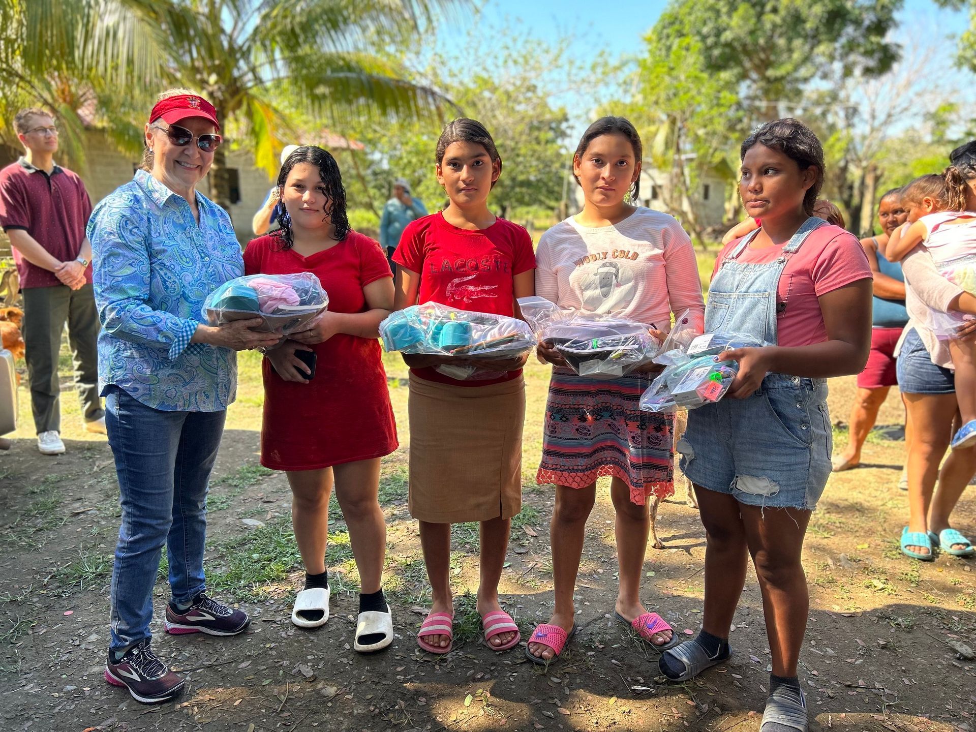 A group of young girls are standing next to each other holding baskets of clothes.