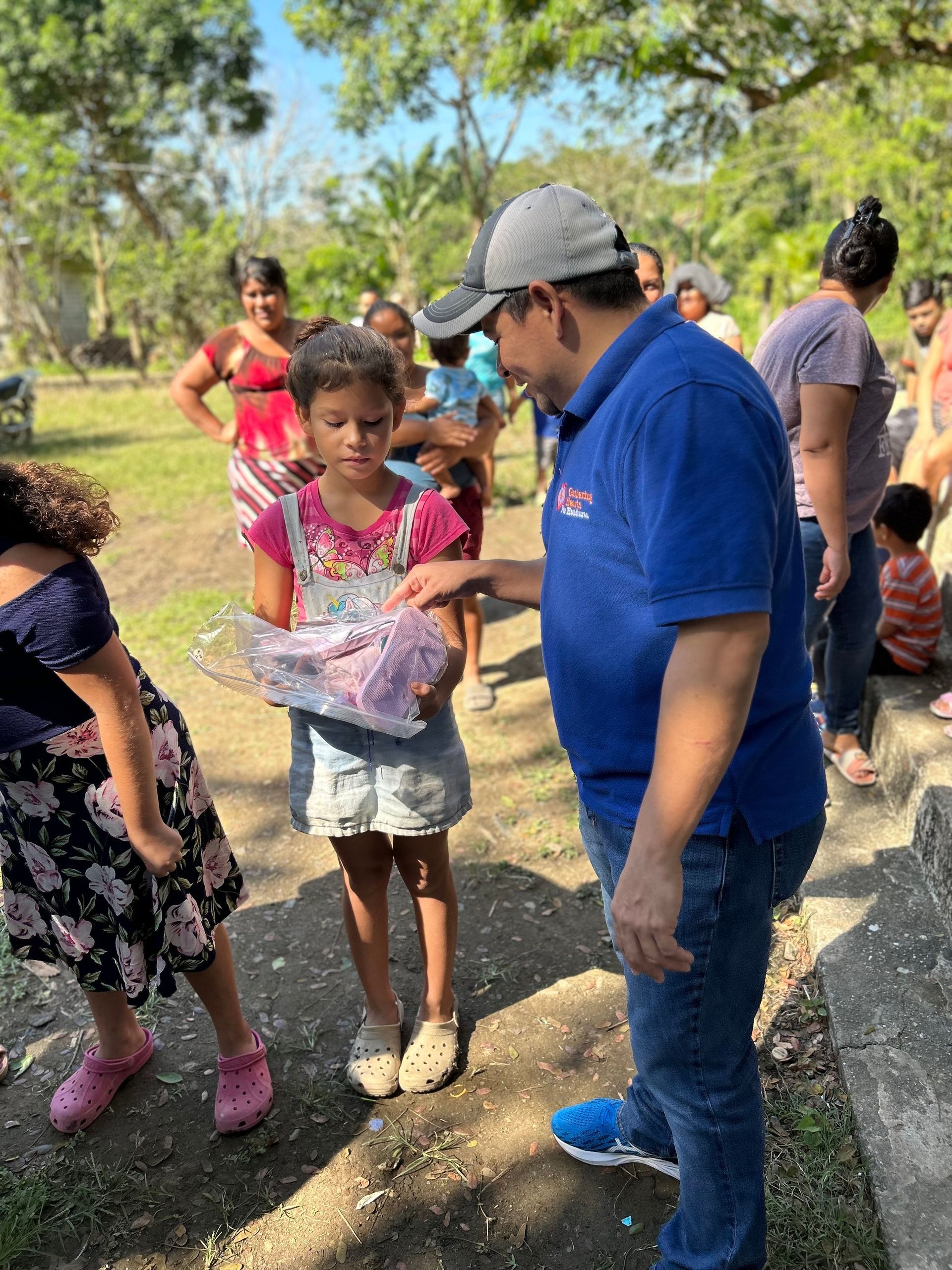 A man is giving a gift to a little girl in a park.