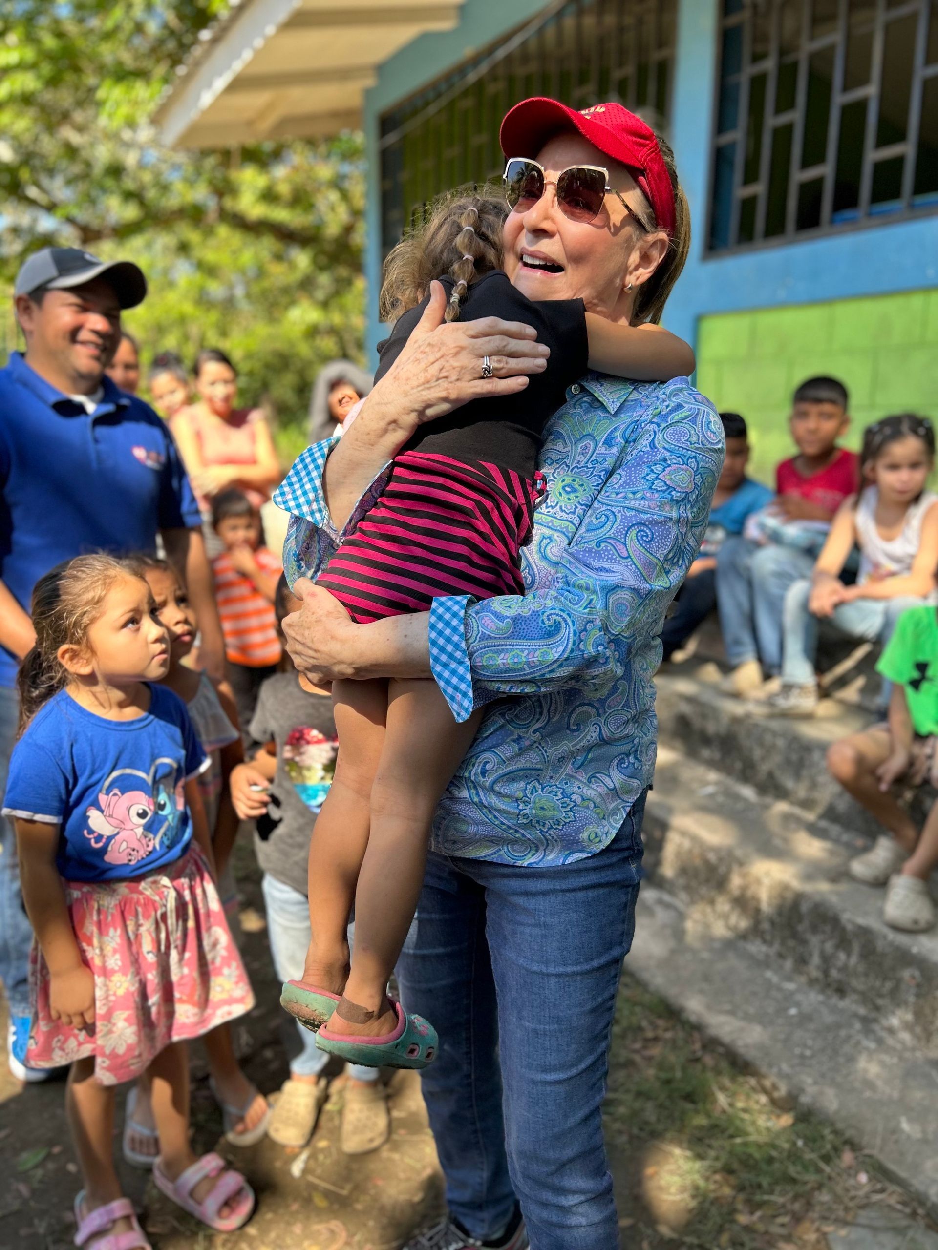 A woman is holding a baby in her arms in front of a group of children.