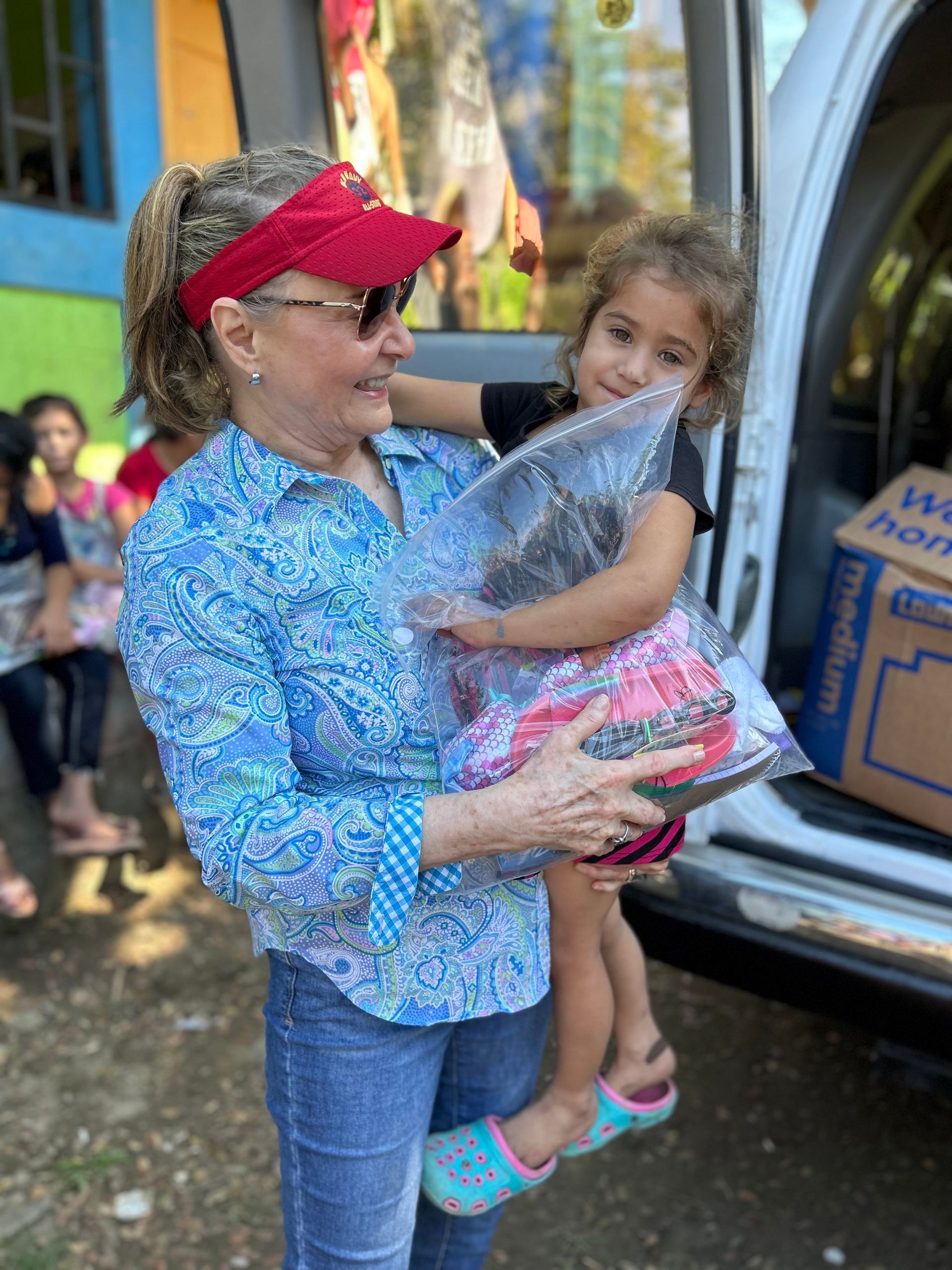 A woman is holding a little girl in her arms in front of a van.