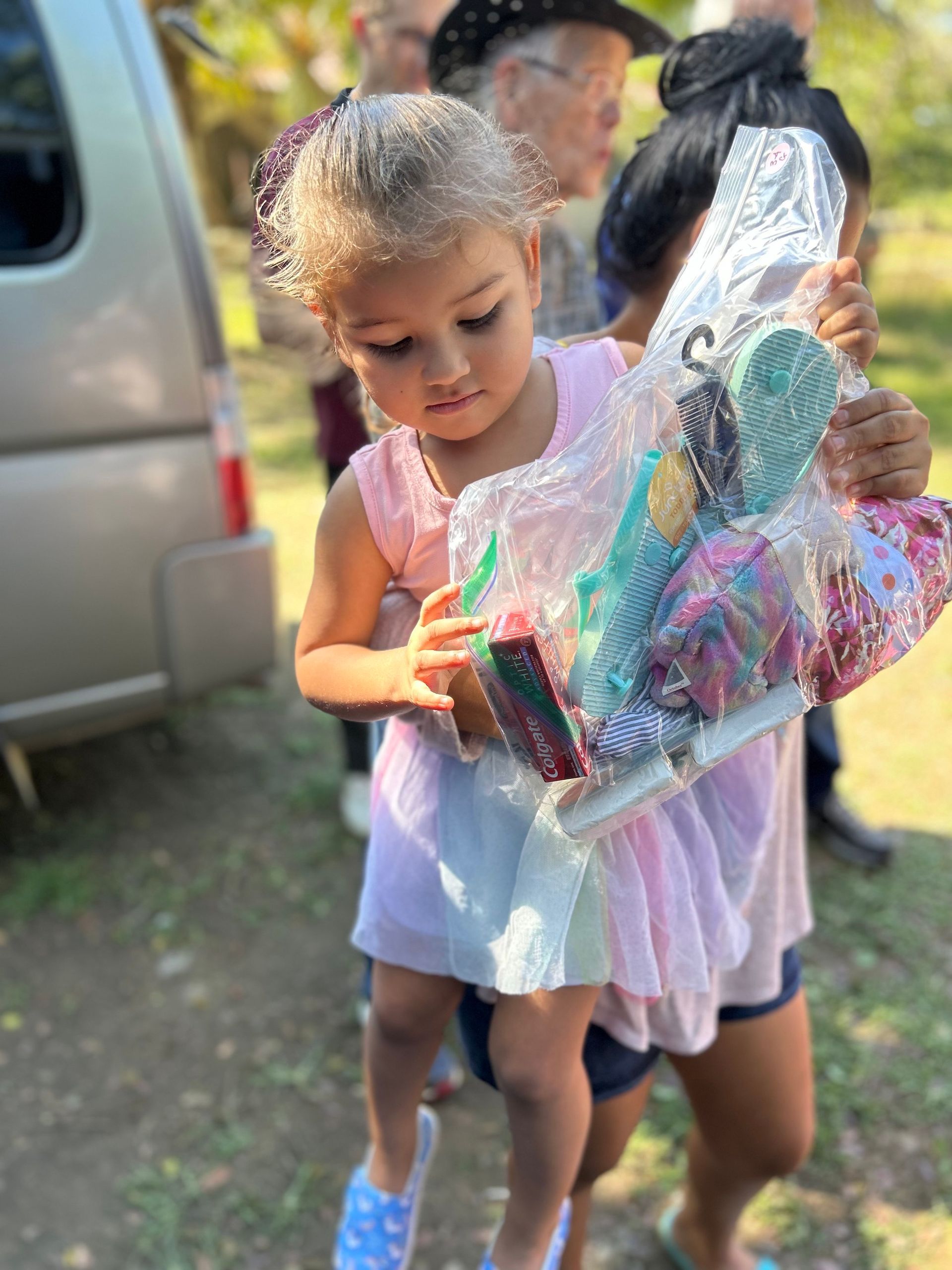 A little girl is carrying a bag of toys.