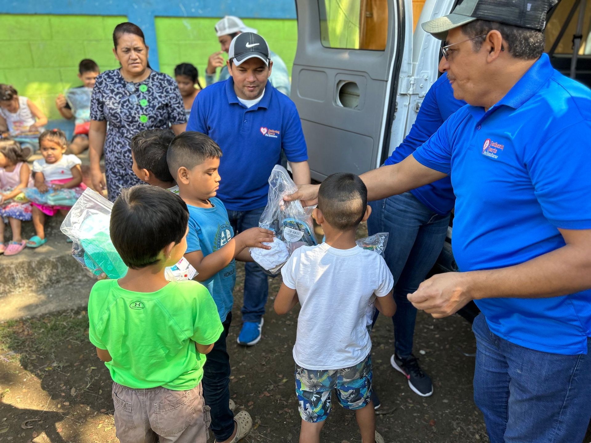 A group of people are standing around a group of children.