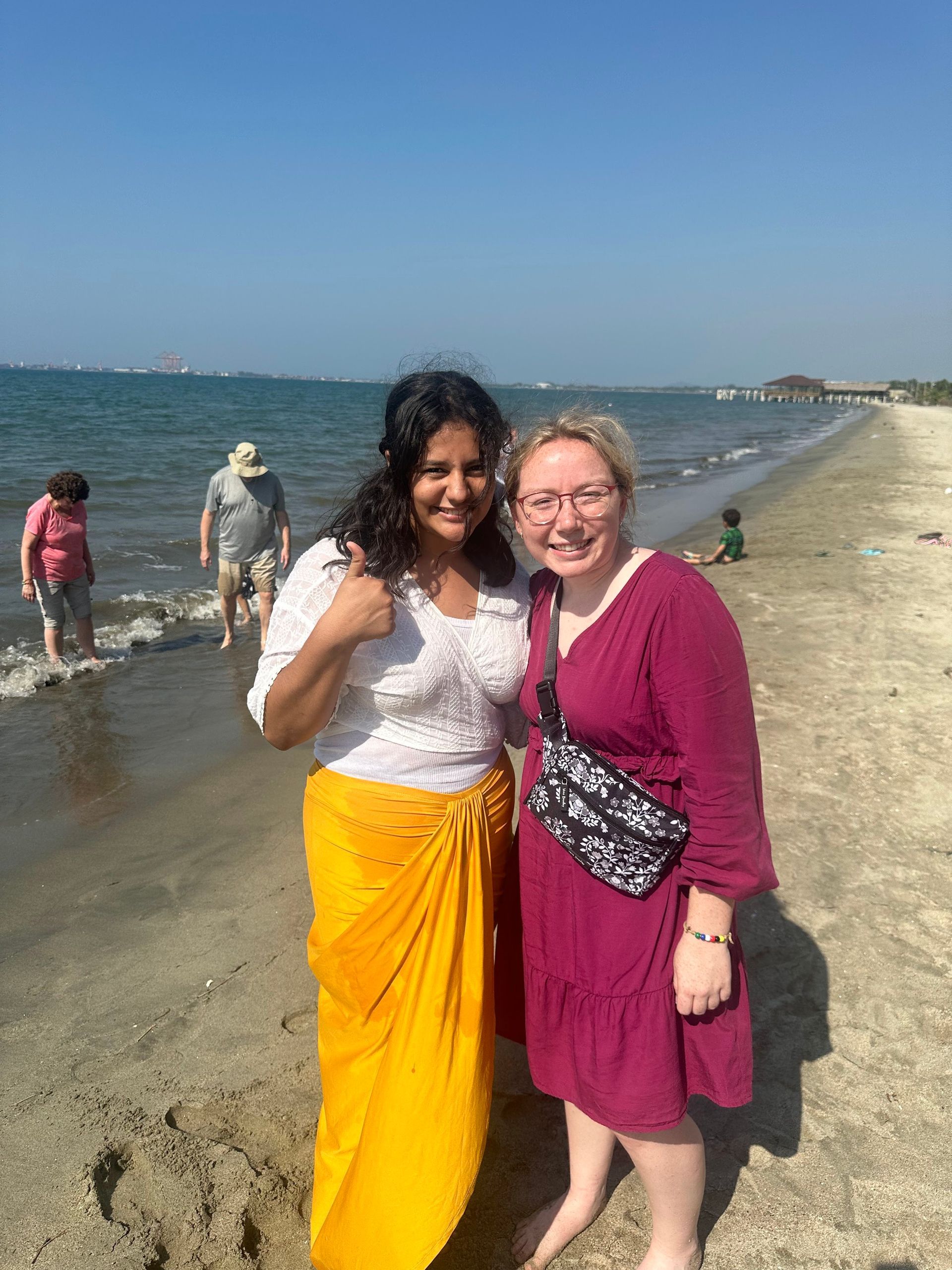 Two women are posing for a picture on the beach.
