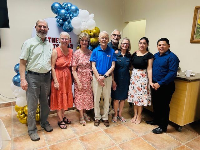A group of people are posing for a picture with balloons in the background