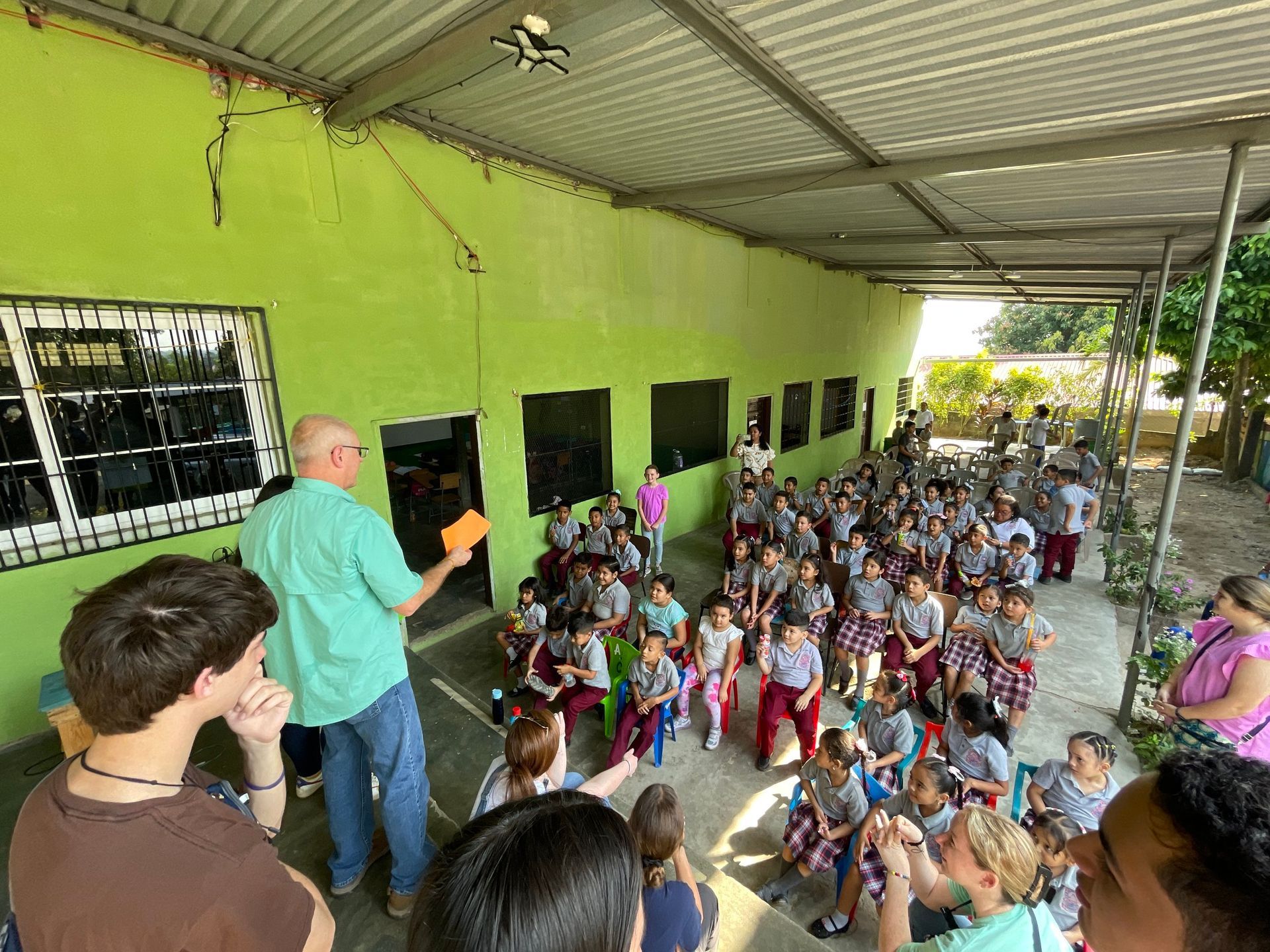 A group of people are standing in front of a green building.
