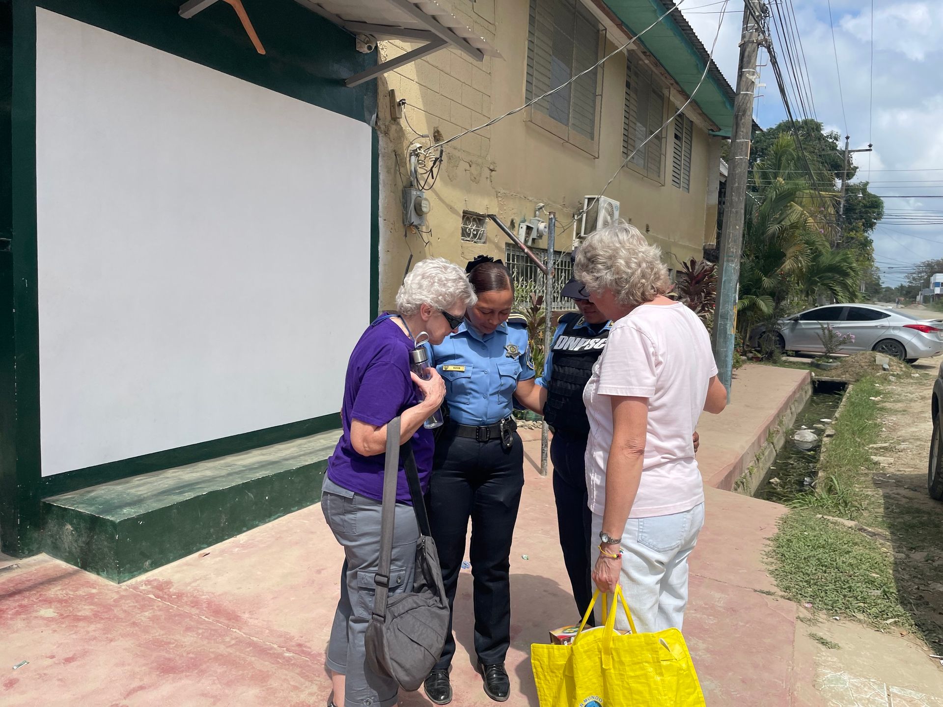 A woman in a police uniform is talking to two other women.