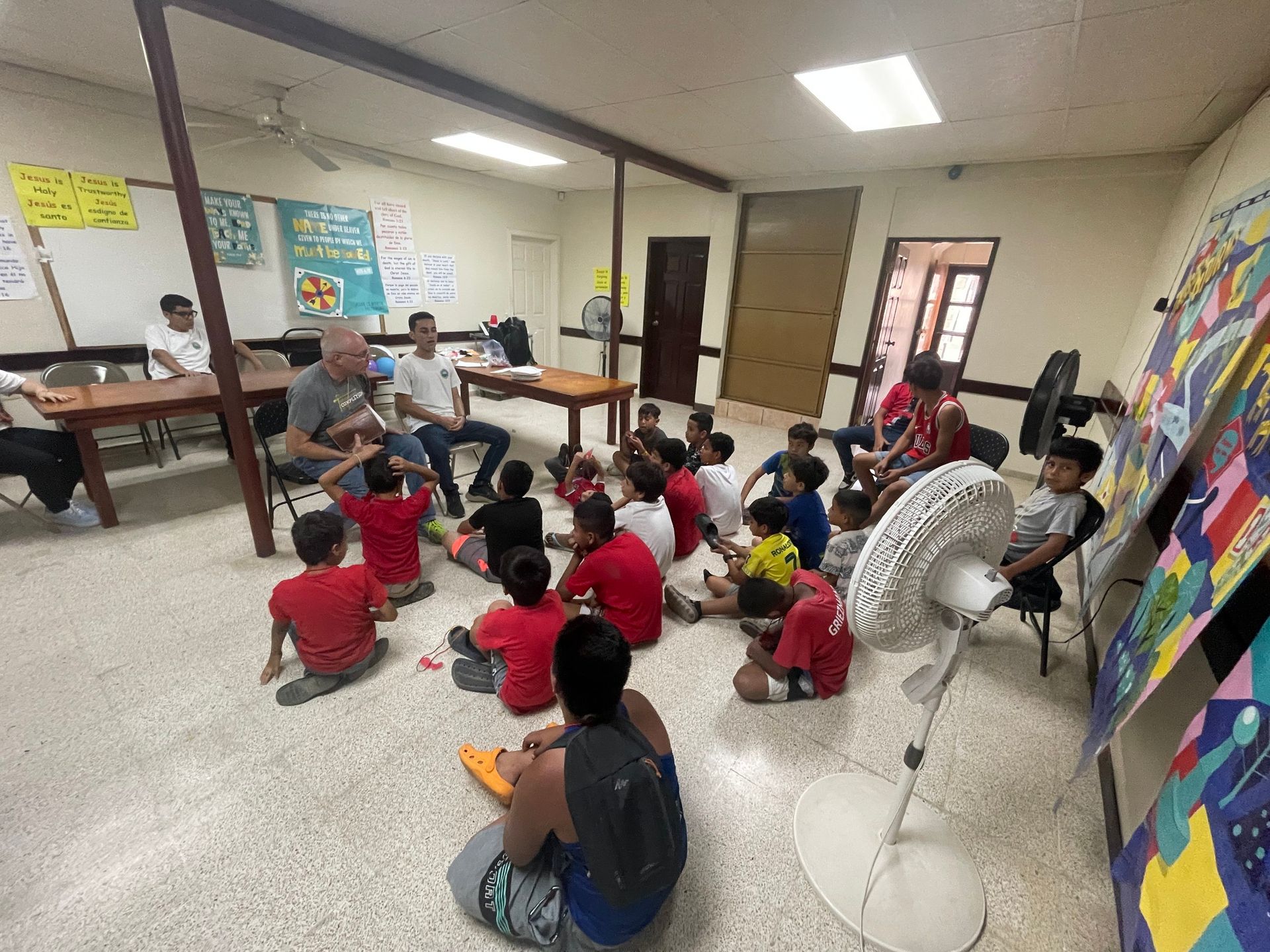 A group of children are sitting on the floor in a room.