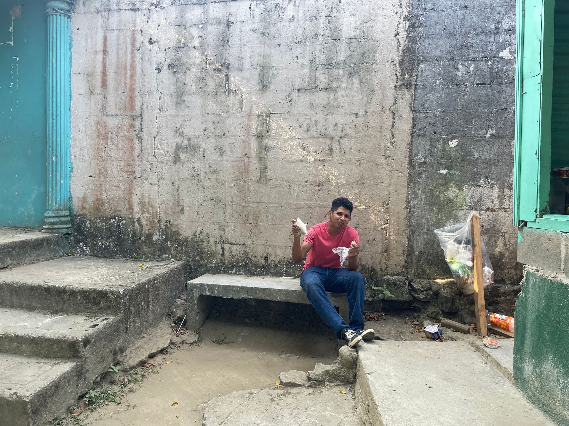 A man is sitting on a bench in front of a wall.