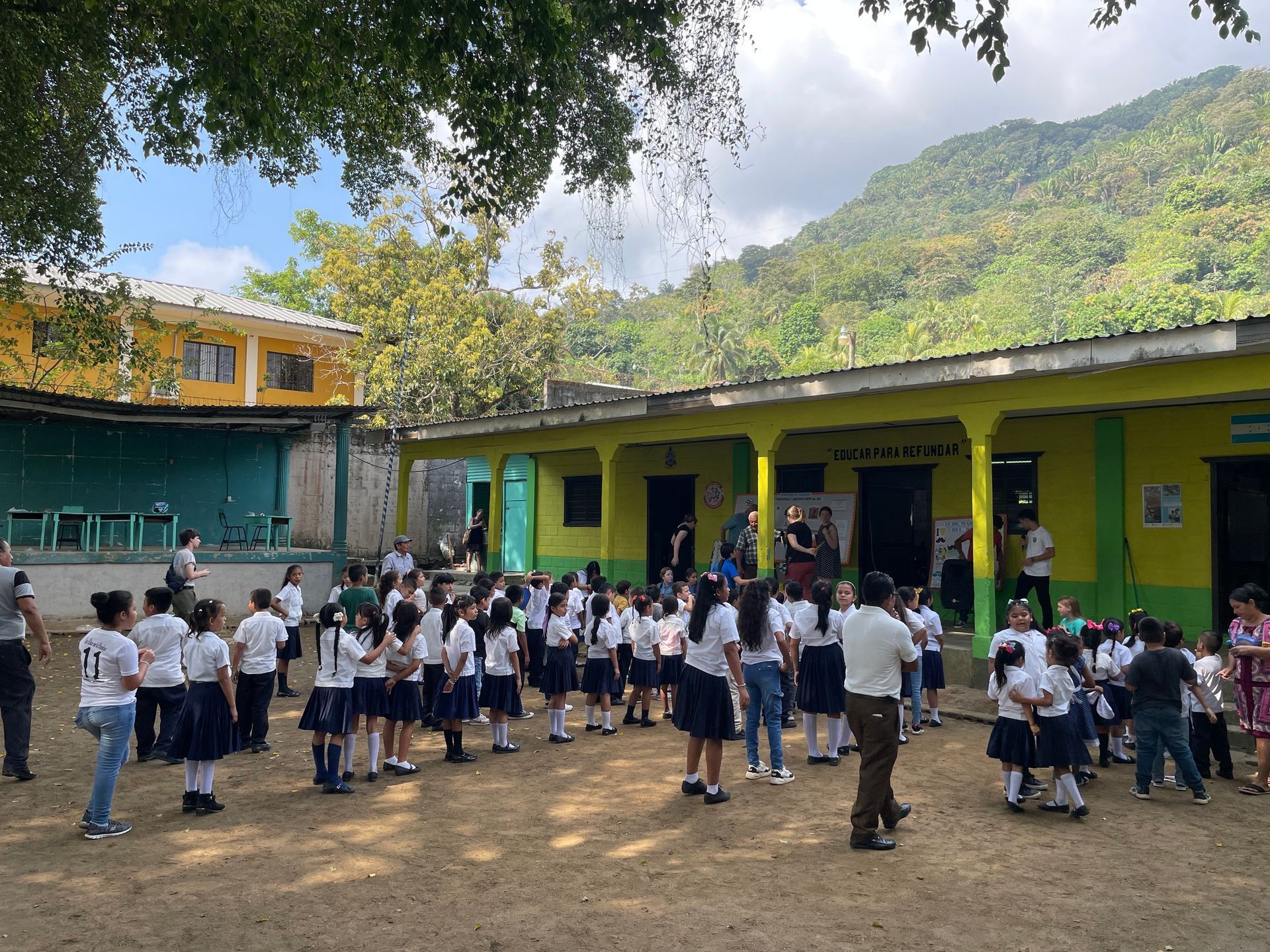 A group of children are standing in front of a school building.