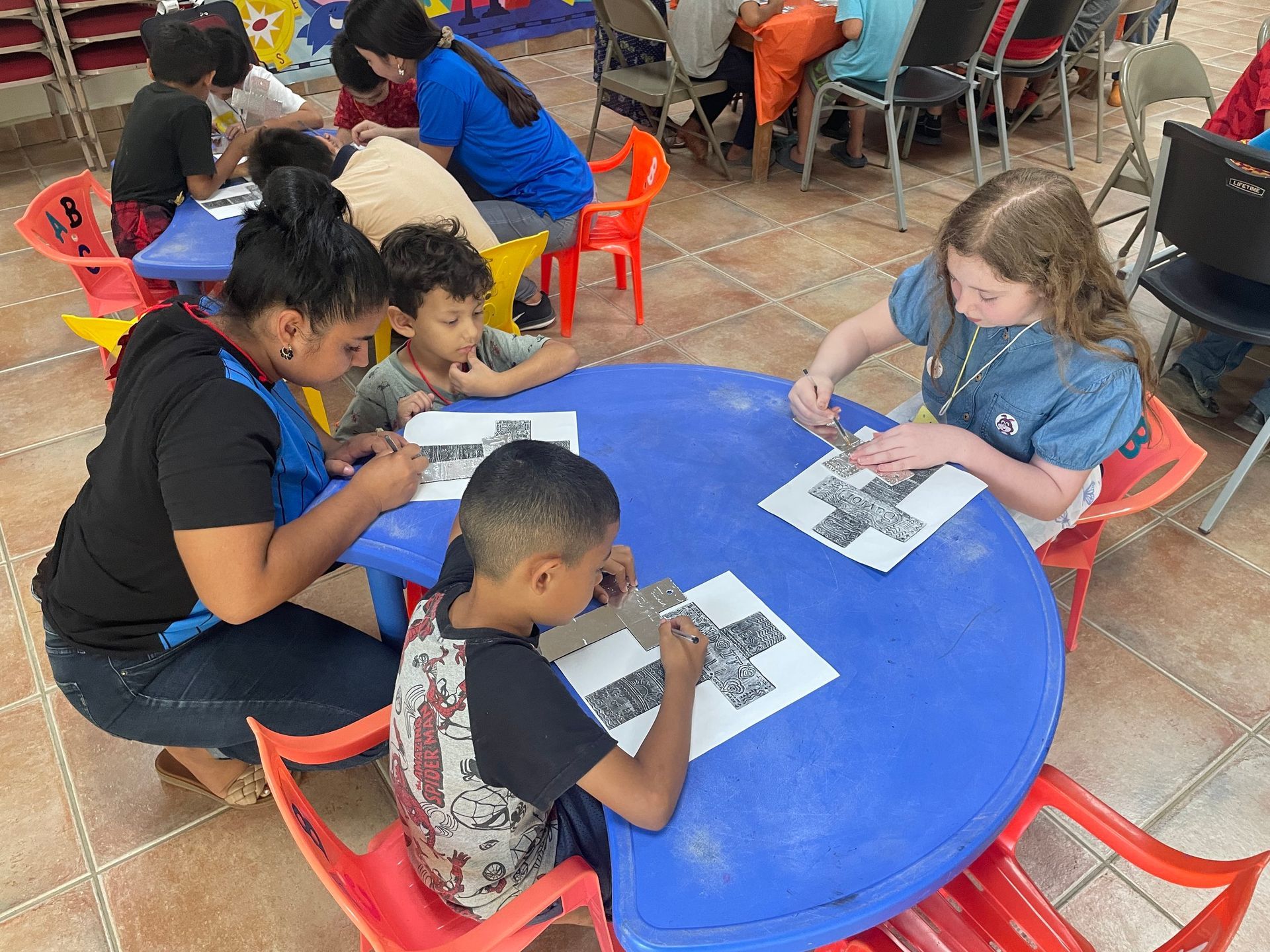 A group of children are sitting around a blue table.