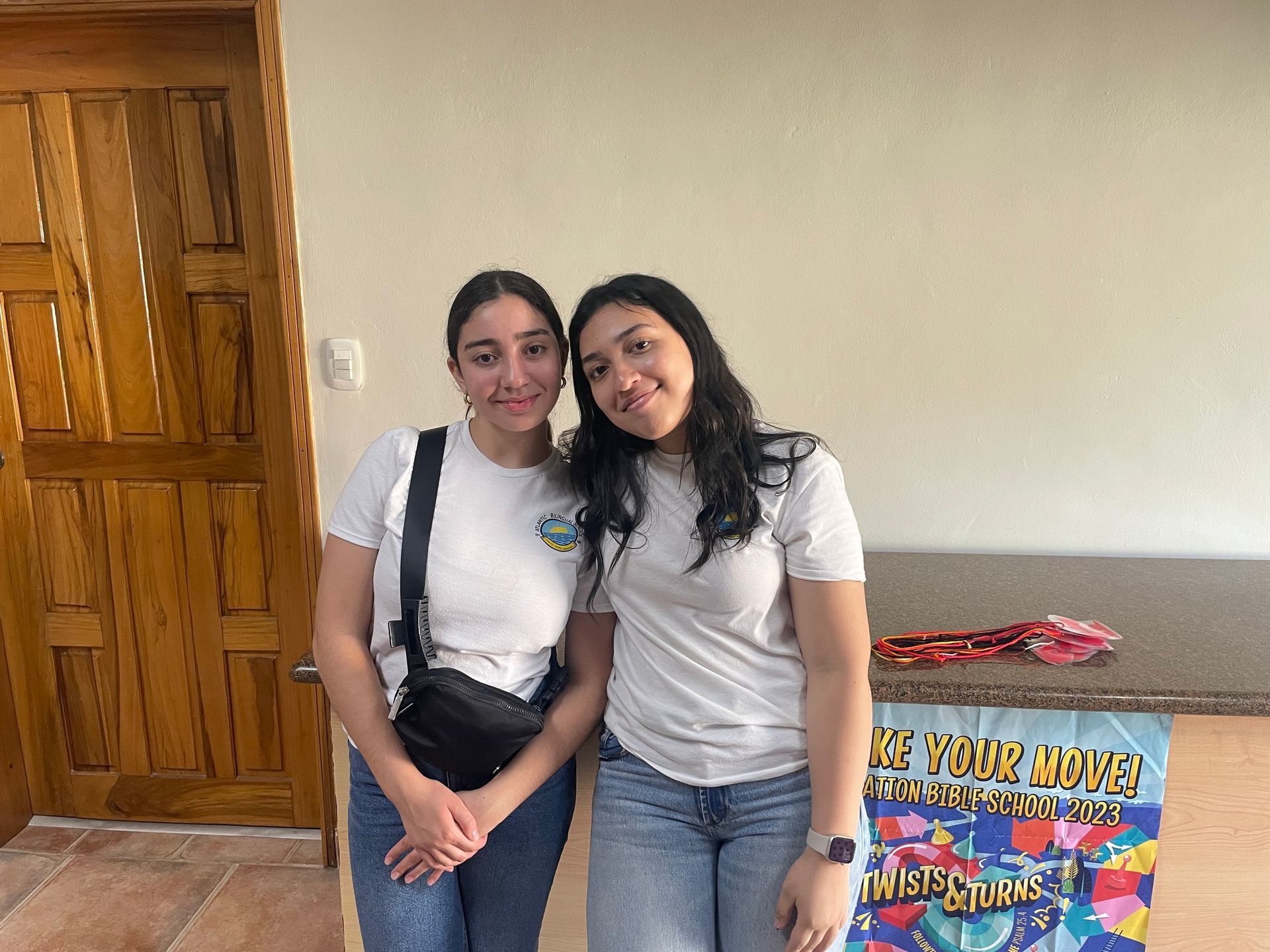 Two young women are posing for a picture in a room.