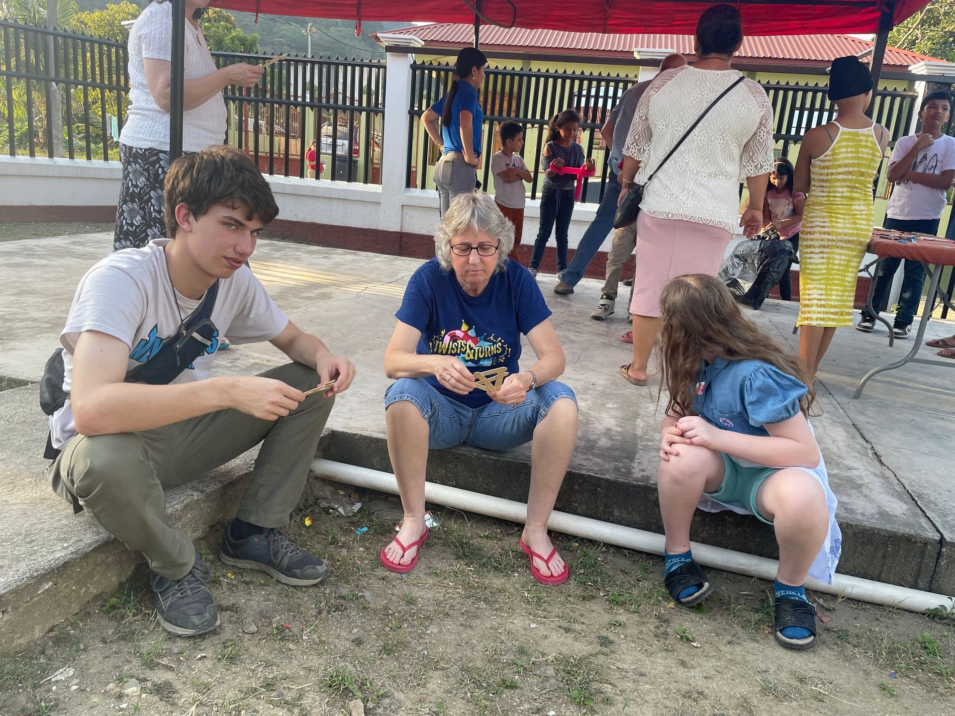 A group of people are sitting on the ground under a tent.