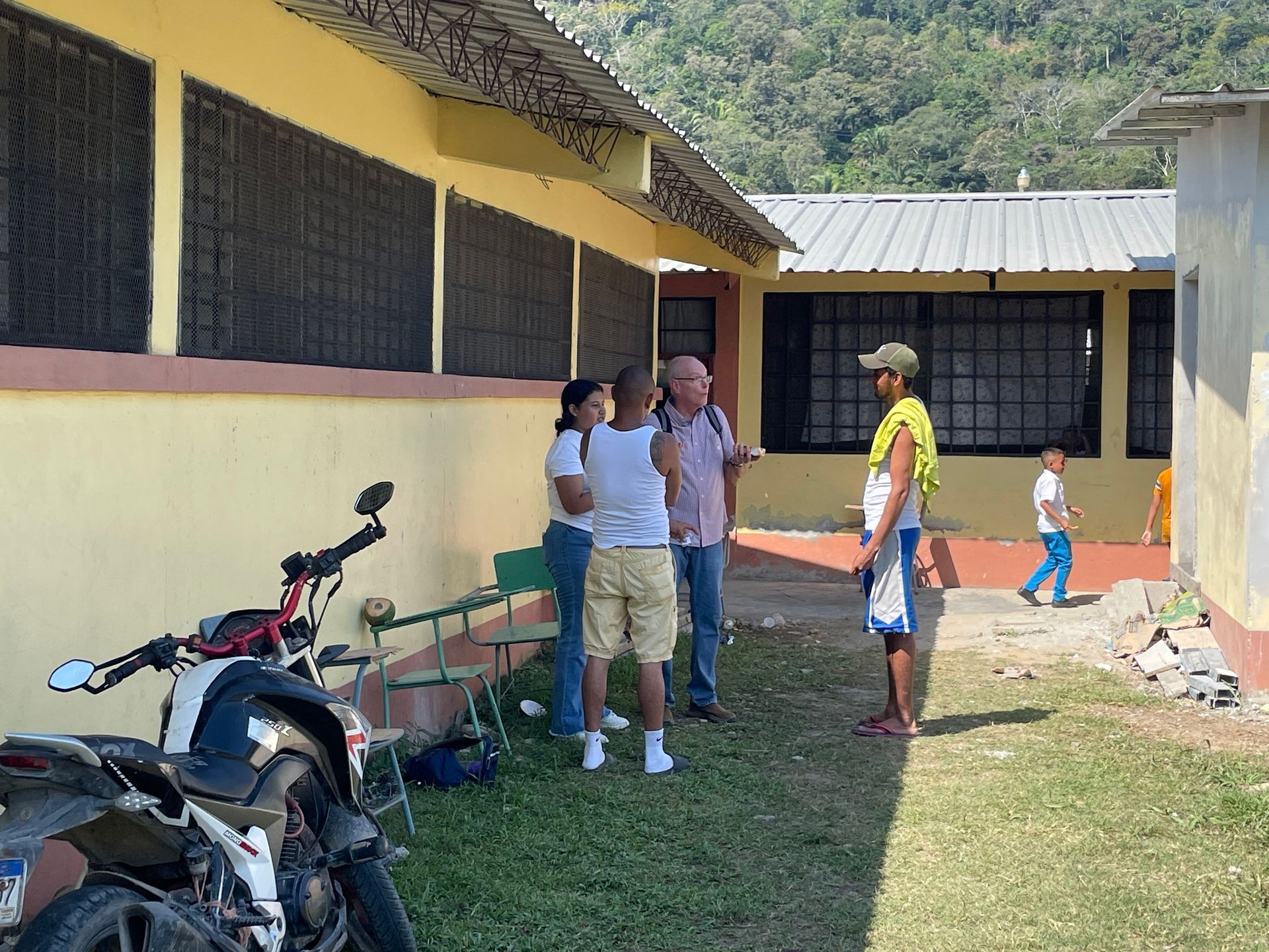 A group of people standing outside of a building with a motorcycle parked in front of them