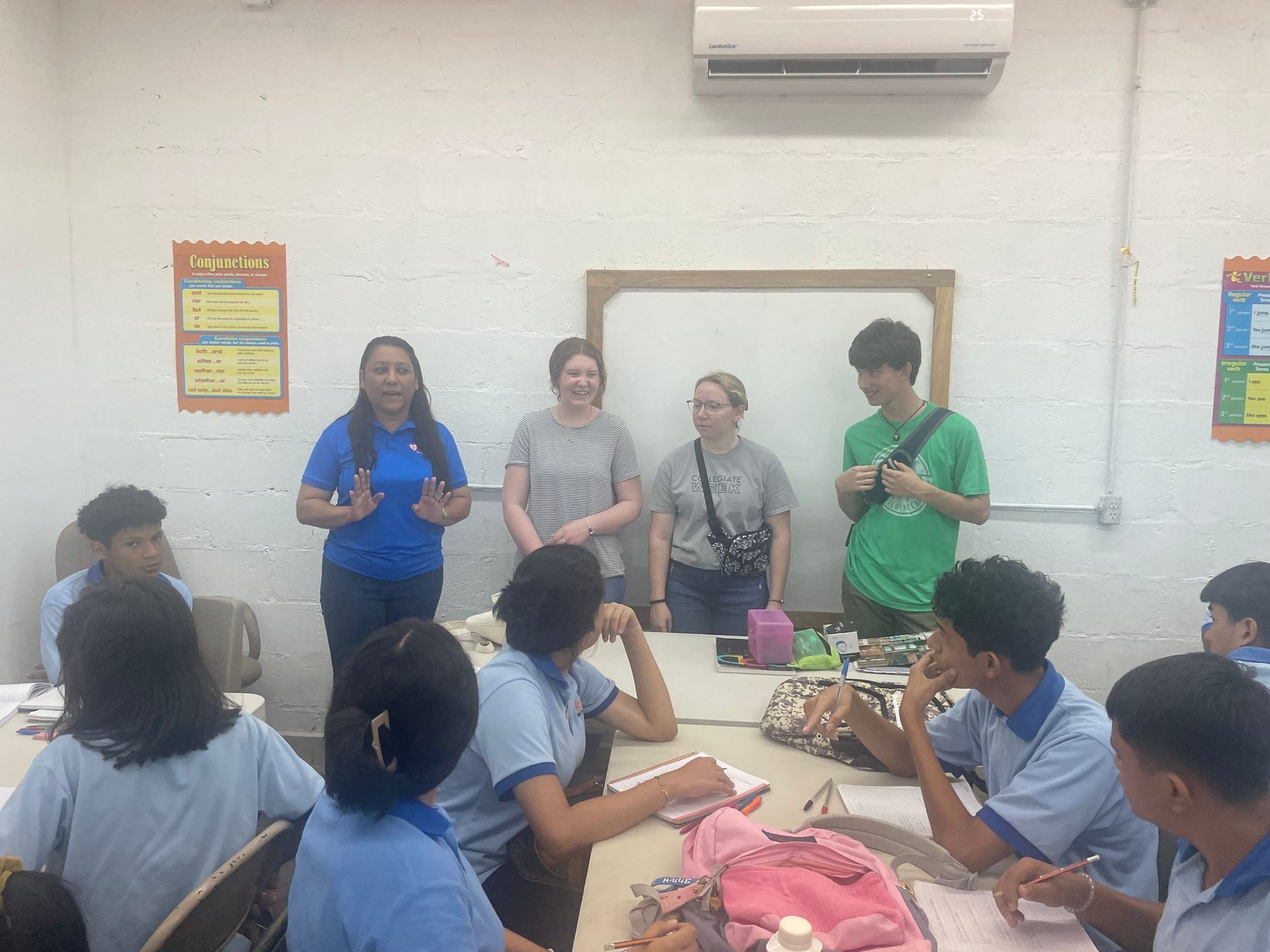 A group of people are sitting around a table in a classroom.