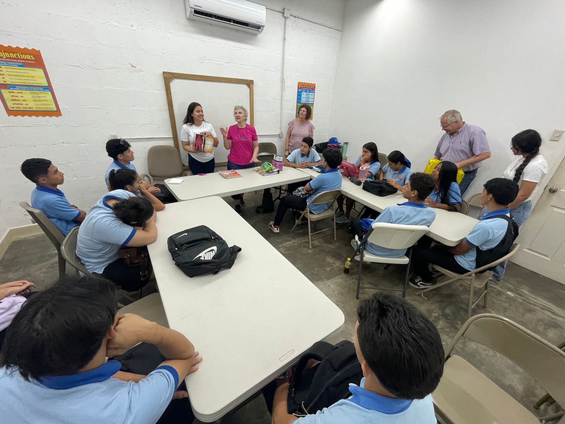 A group of children are sitting at tables in a classroom.