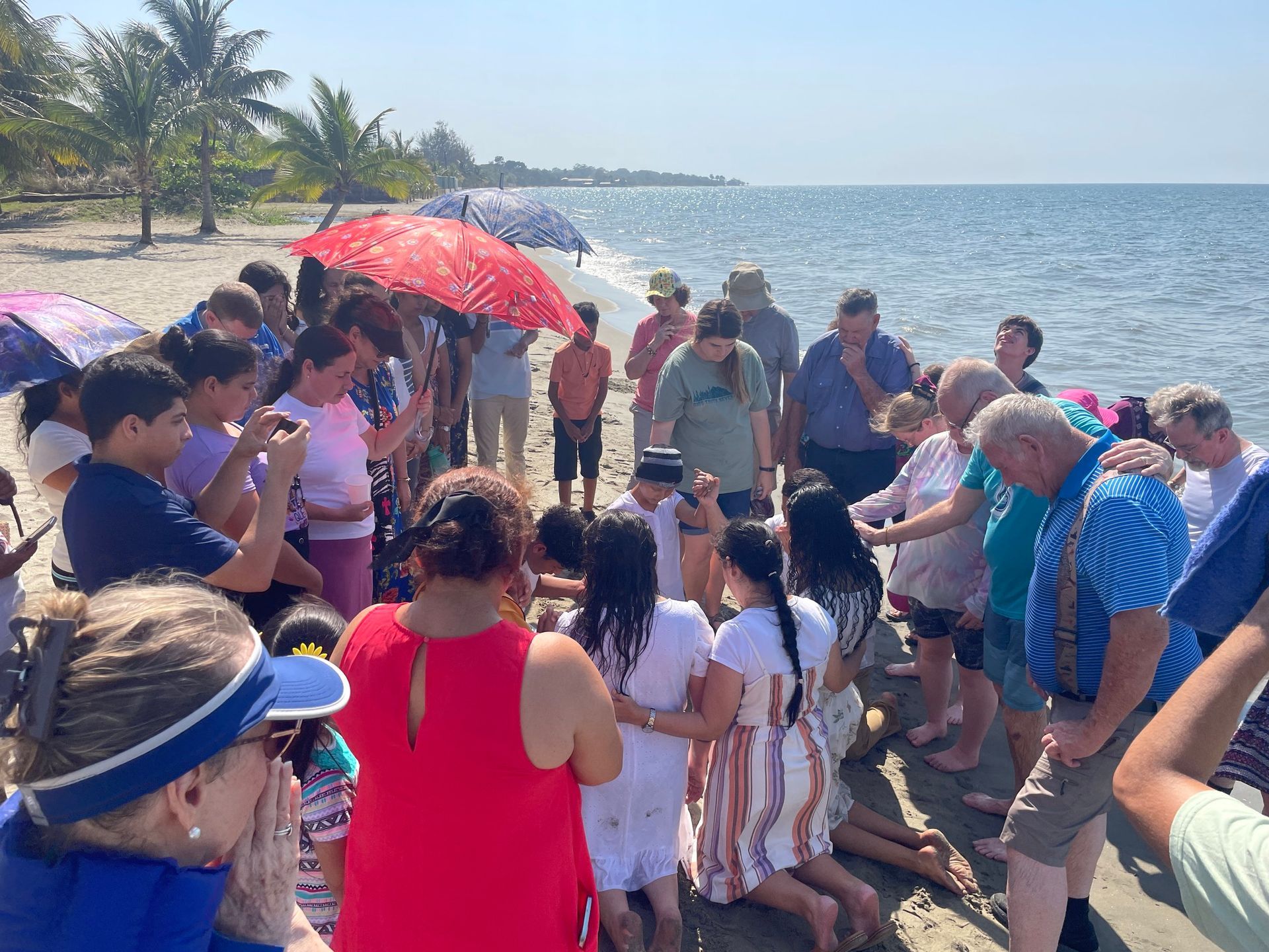 A group of people are standing on a beach near the ocean.