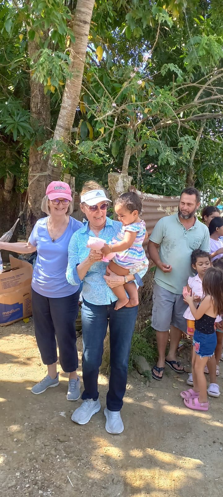 A woman is holding a baby in her arms while standing next to a group of people.