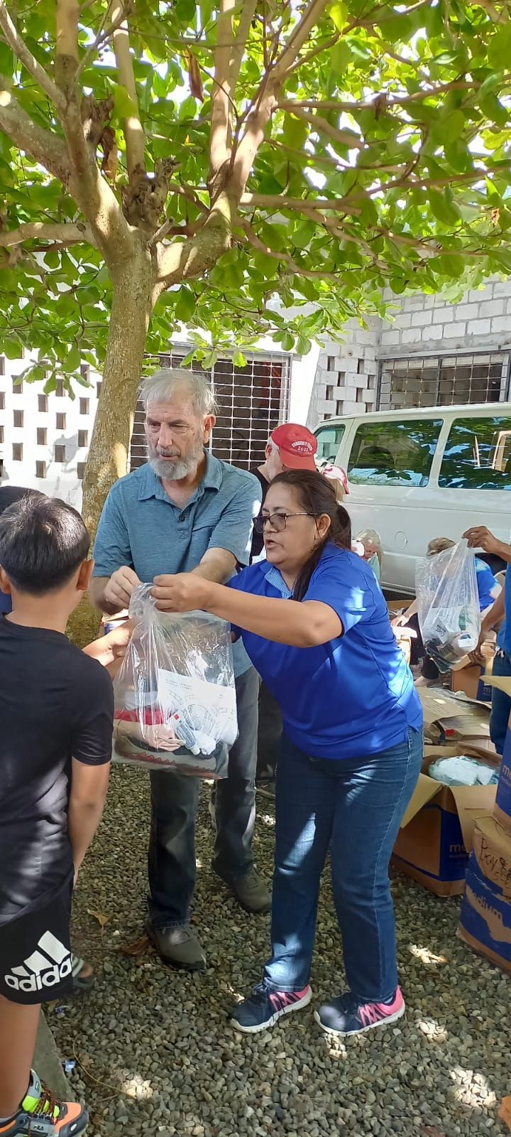 A woman in a blue shirt is holding a bag of food while standing next to a man and a boy.