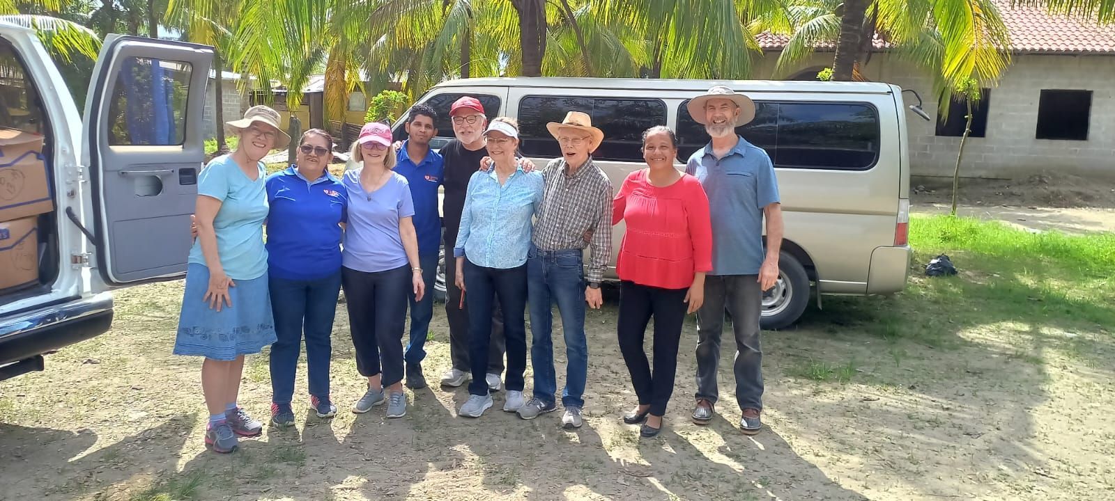 A group of people are posing for a picture in front of a van.