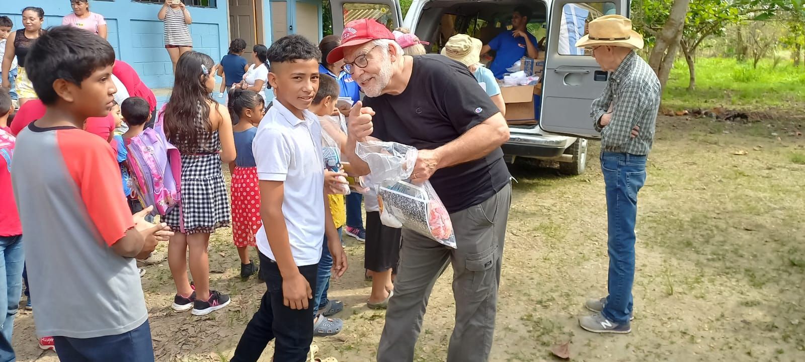 A group of people are standing around a man holding a bag of food.