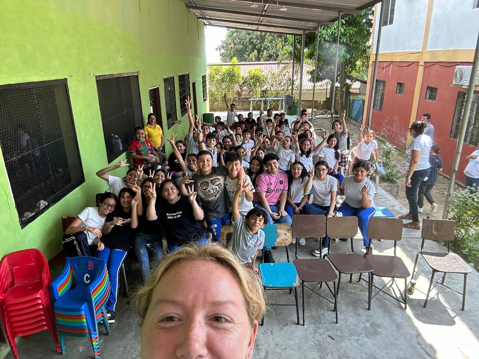 A woman is taking a selfie with a group of people sitting in chairs.