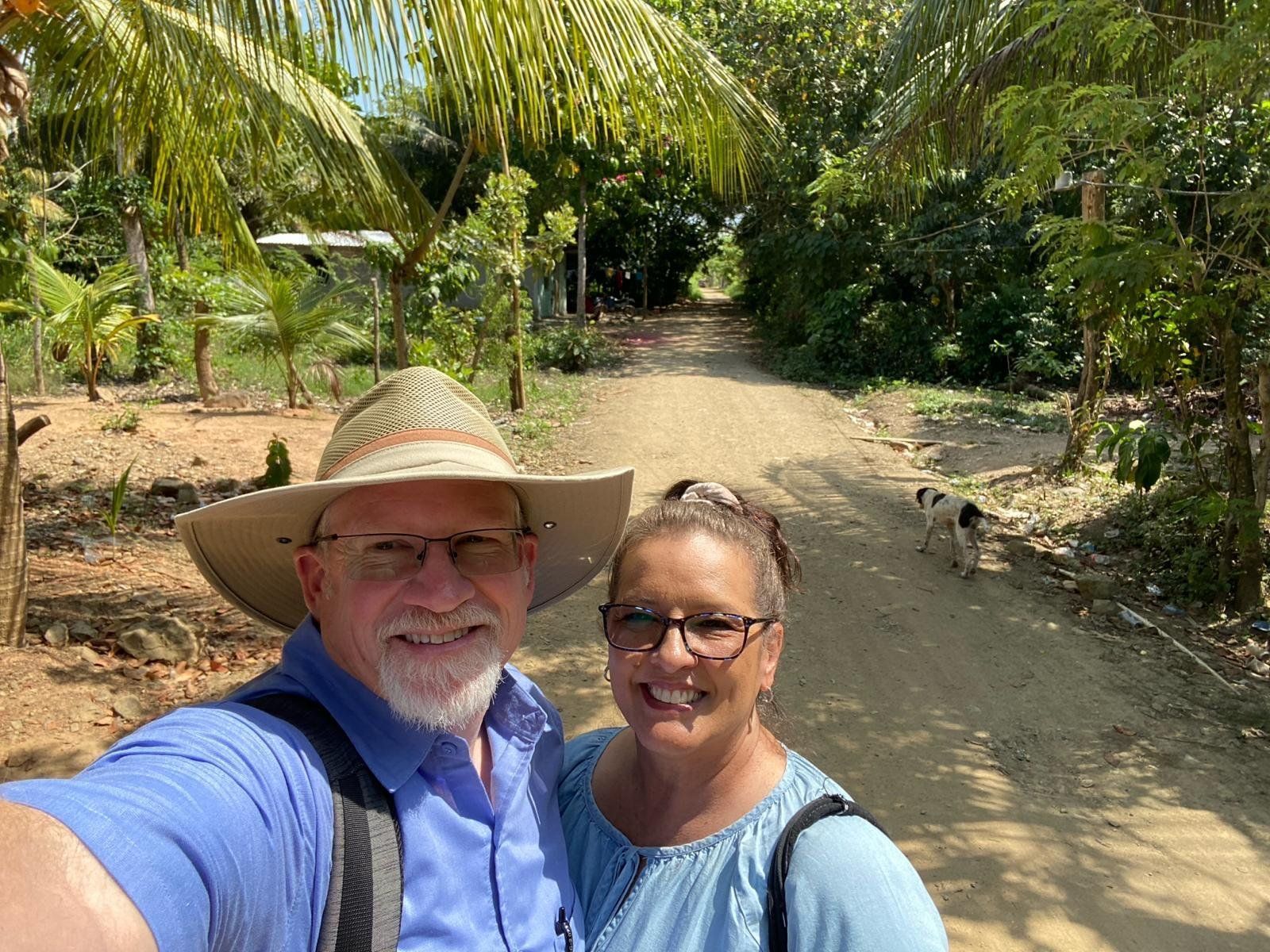A man and a woman are taking a selfie on a dirt road.