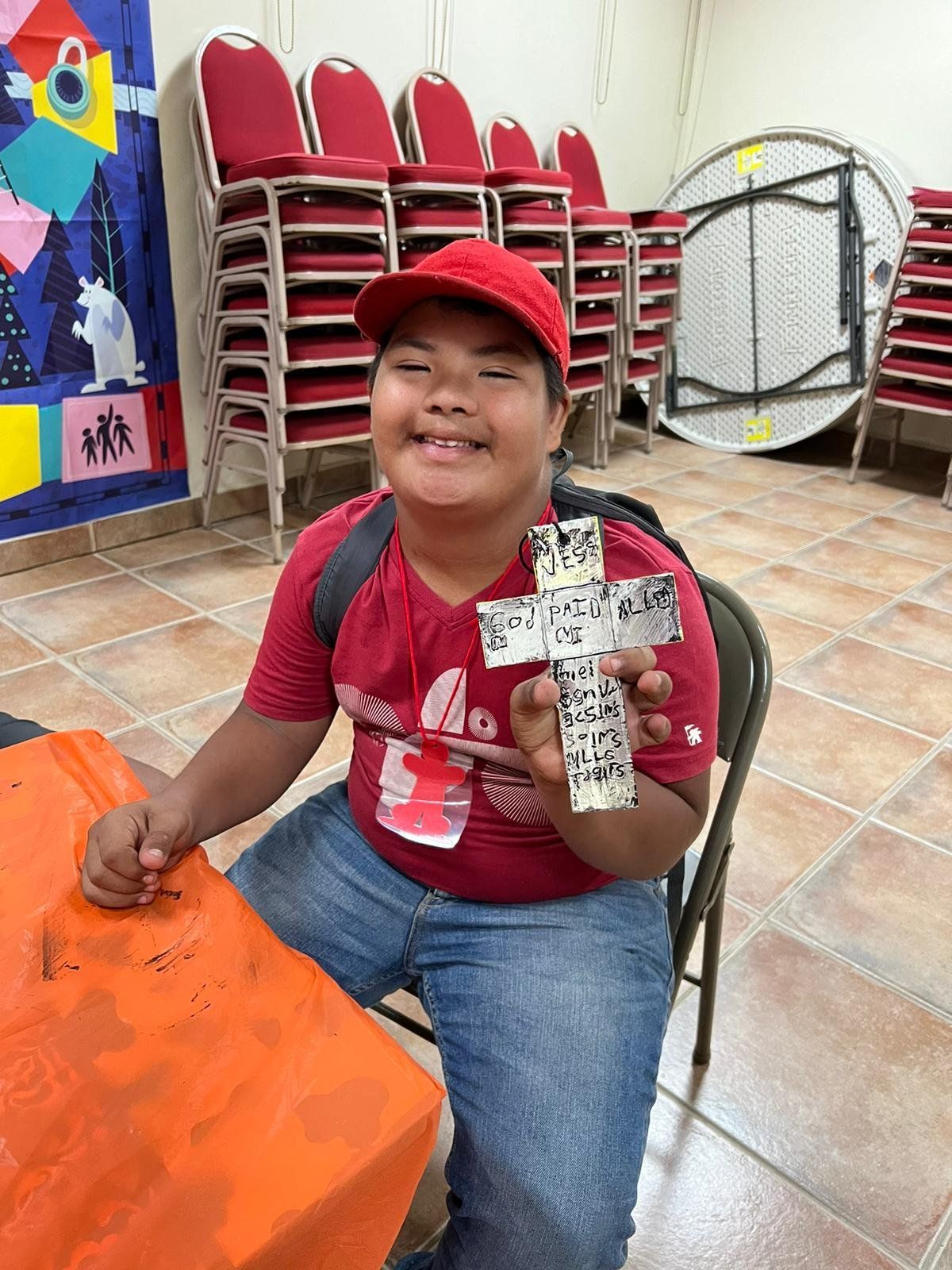 A young boy is sitting at a table holding a cross.