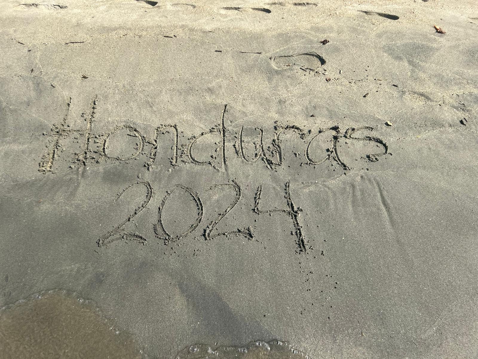 The year 2021 is written in the sand on the beach.