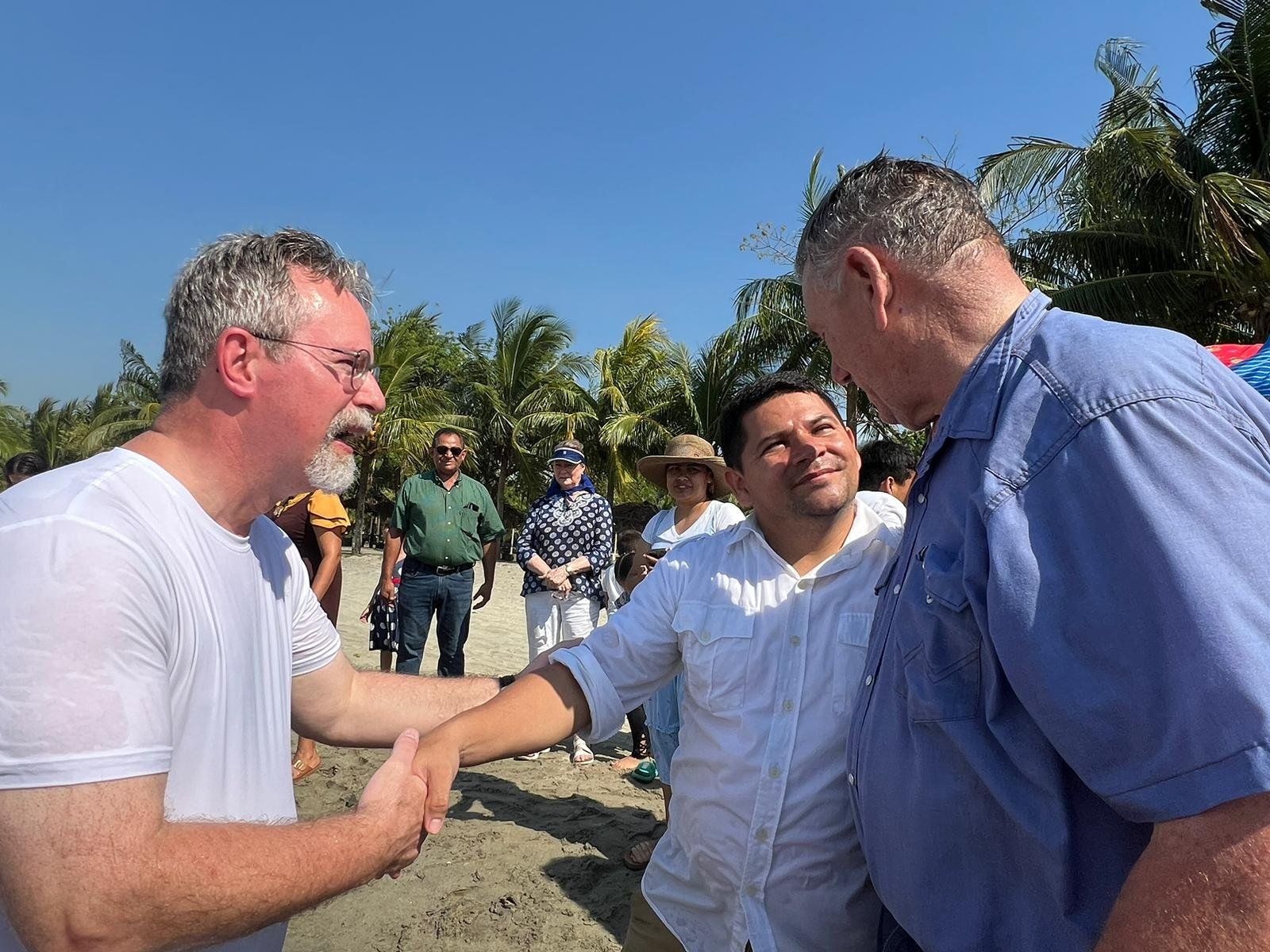 A group of men are shaking hands on a beach.