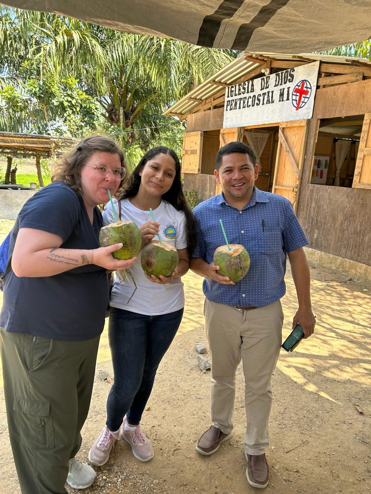 Three people are standing next to each other holding coconuts.