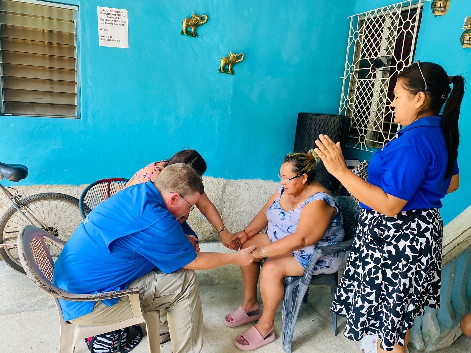 A group of people holding hands in a room with a blue wall