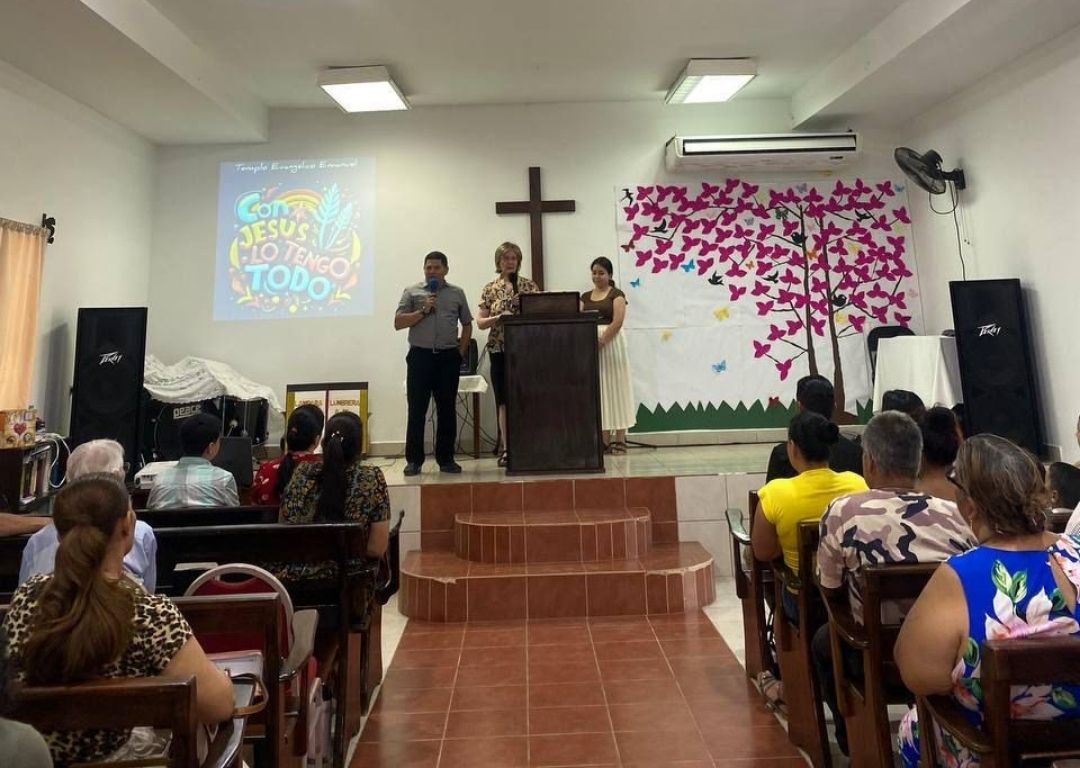 A group of people are sitting in a church watching a presentation.