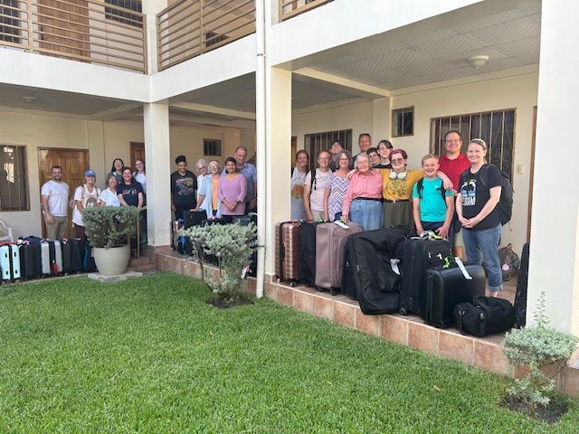 A group of people standing in front of a building with luggage.