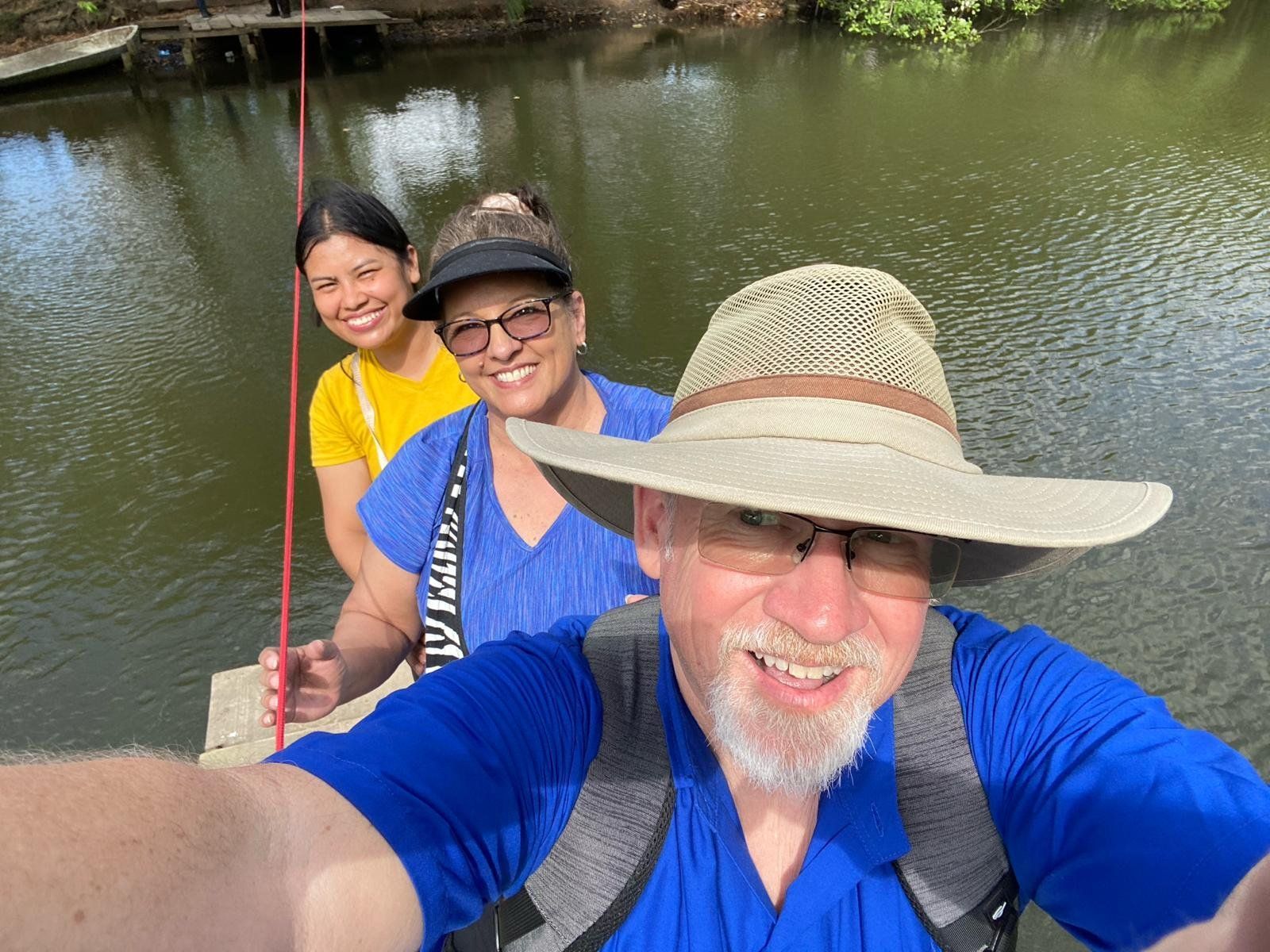 A man in a hat is taking a selfie with two women.