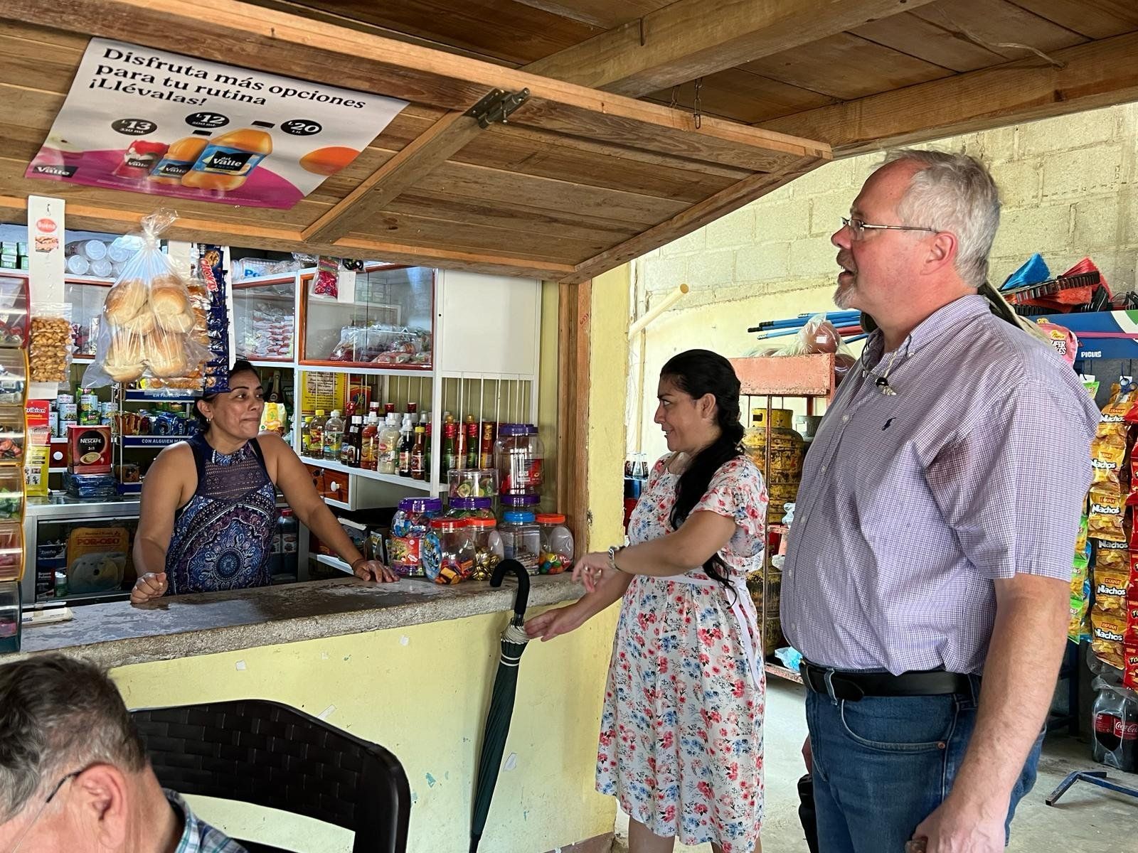 A man and a woman are standing in a store talking to each other.