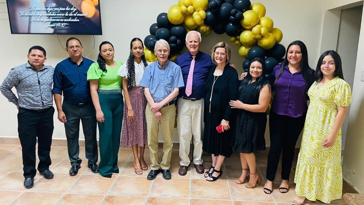 A group of people are posing for a picture in front of balloons.