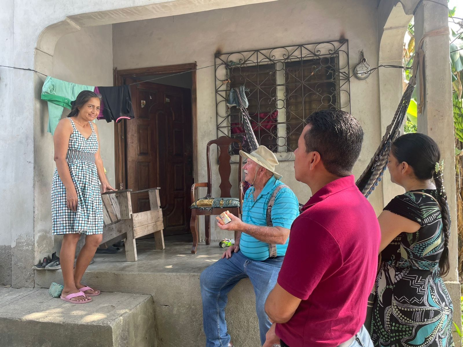 A group of people are standing outside of a house talking to each other.