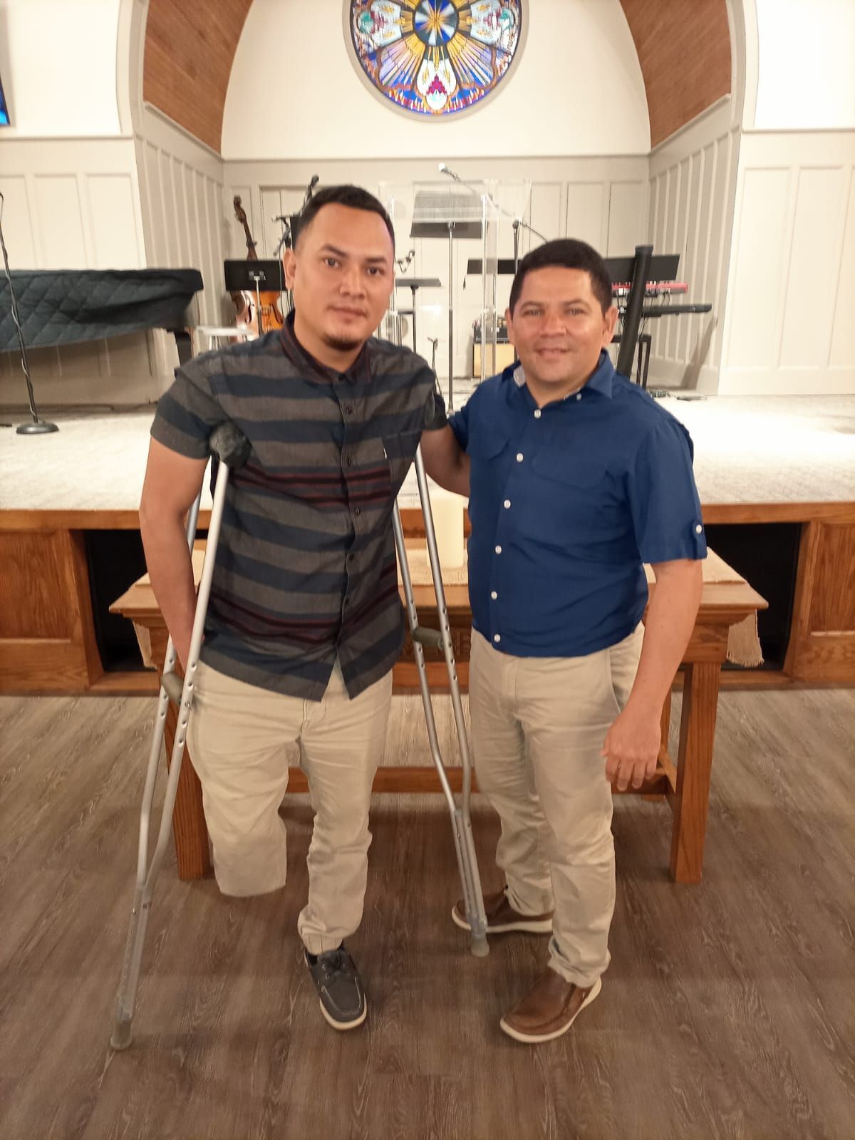 Two men standing next to each other in a church with crutches
