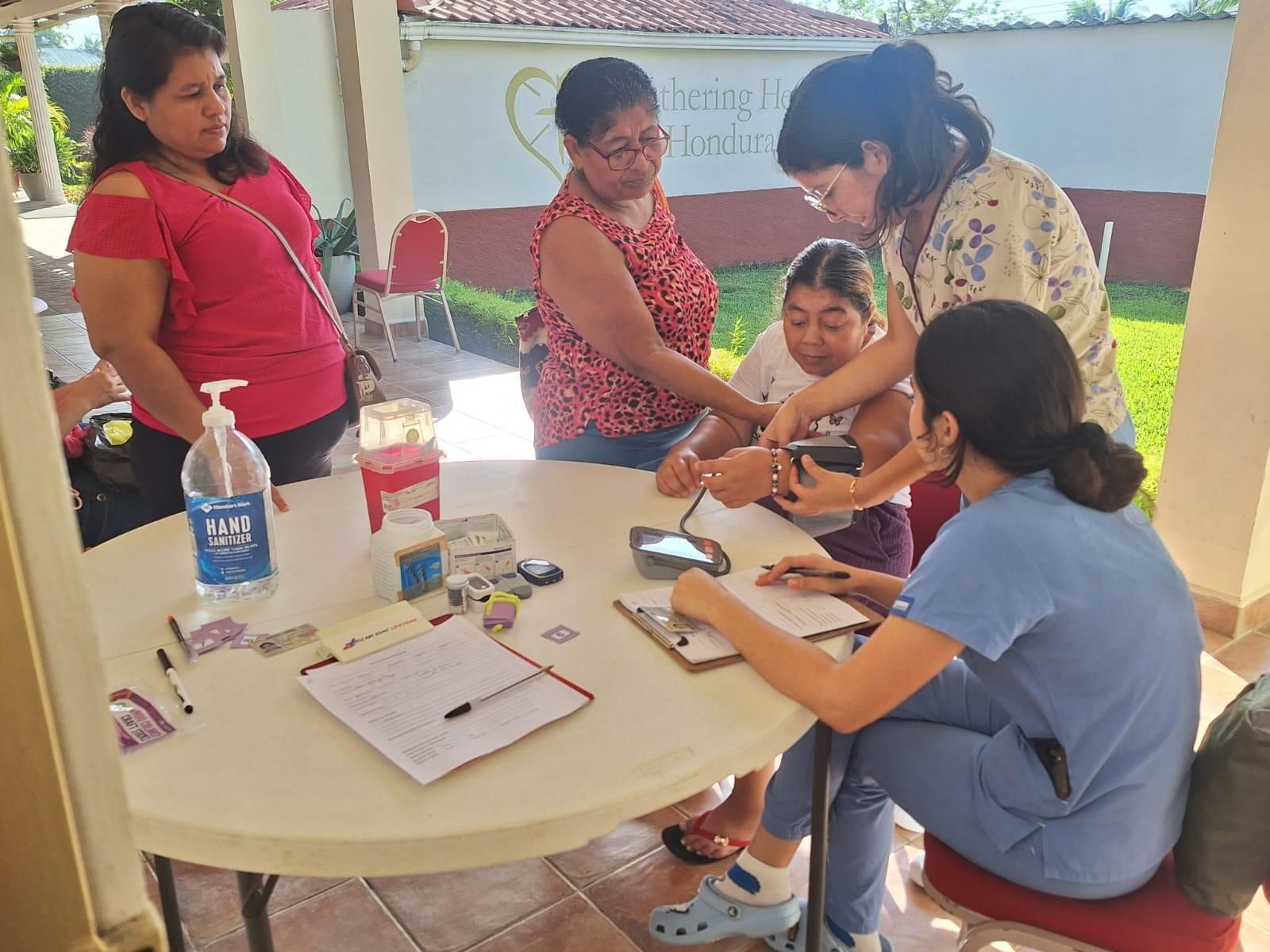A group of women are sitting around a table looking at a cell phone.