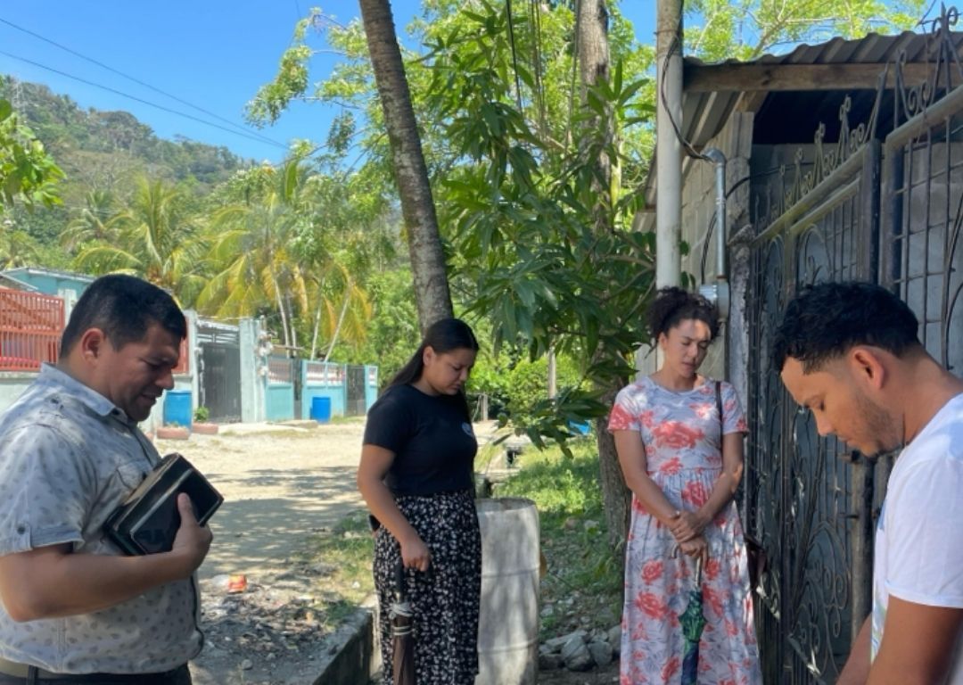 A group of people are praying outside of a building.