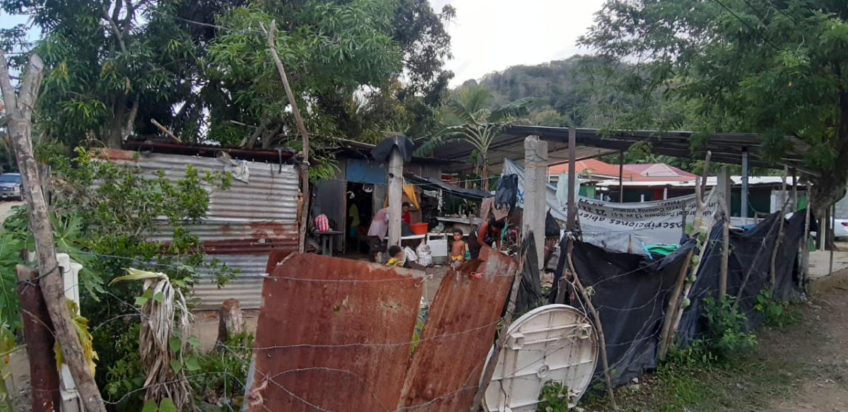 A group of people are standing outside of a shack.