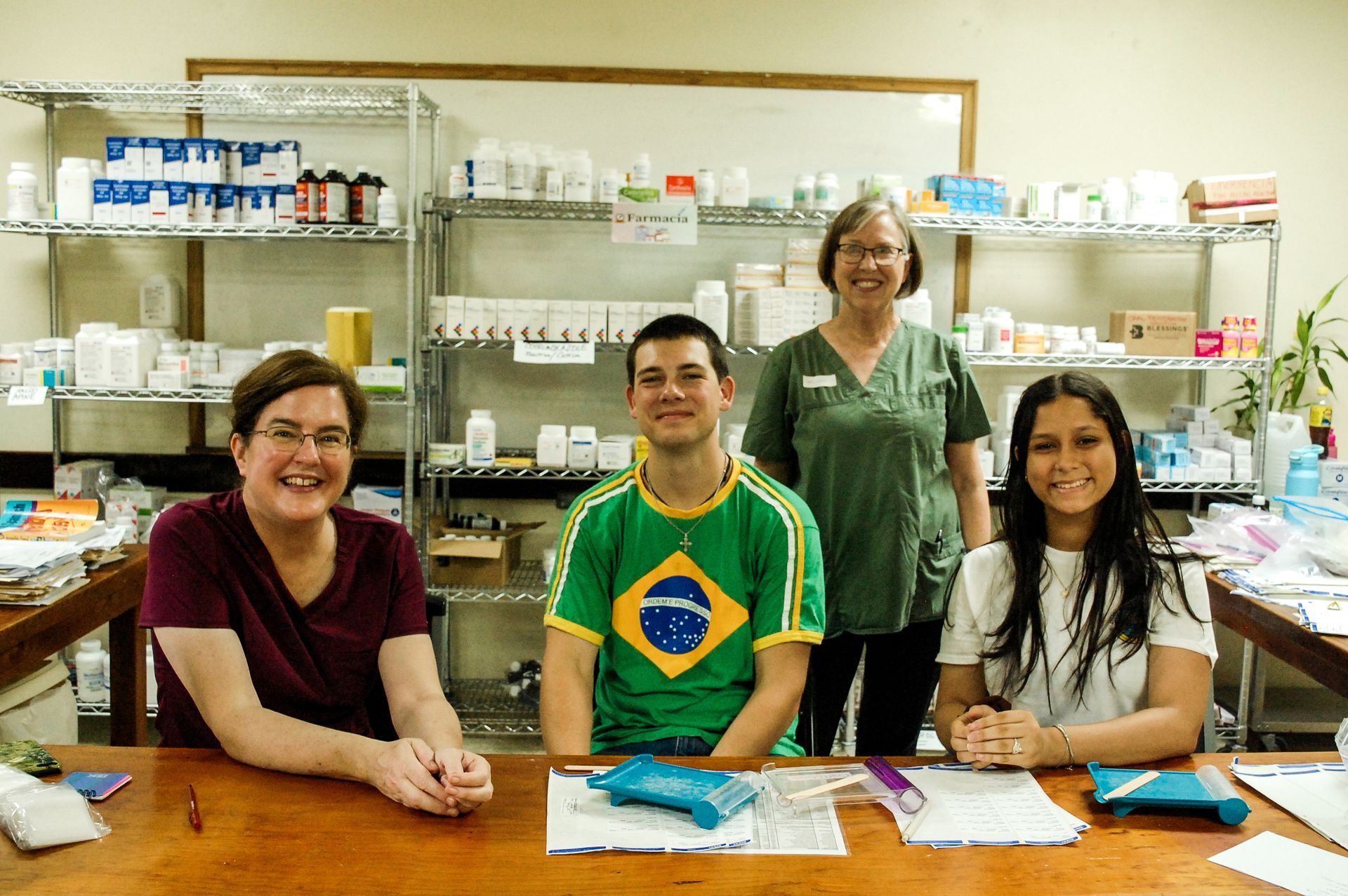 A group of people are sitting at a table in a pharmacy.