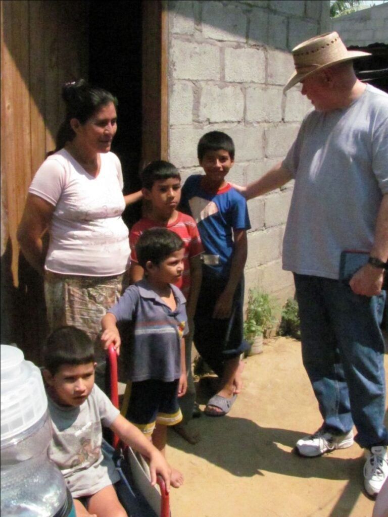 A man in a hat is talking to a group of children