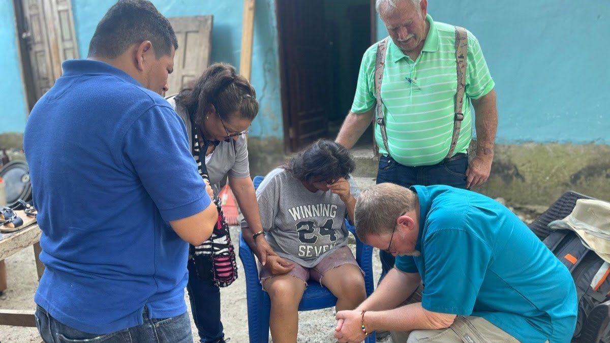 A group of people are kneeling down in front of a blue building.